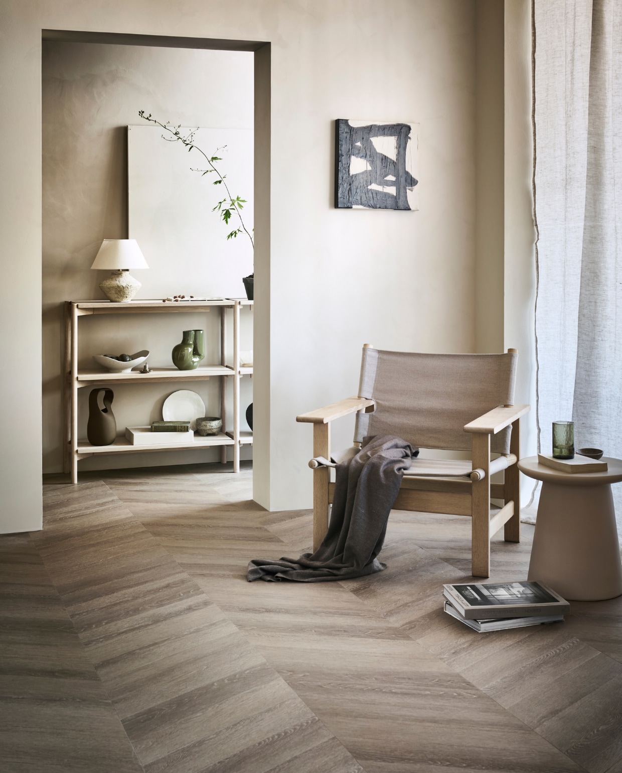pvc-vloer Noble, kleur Sun Kissed, 53,8×11,7 cm, dryback per m² € 48,95 (alleen verkrijgbaar als dryback). M.m.v. pure-original.nl (muurverf Fresco in kleur Old Linnen en Canvas), designtales.nl (fauteuil), vtwonen.be (houten sidetable van Vestbjerg, groene vaas van Hay, bruine vaas van Bloomingville, keramieken kruk van HKliving), instagram.com/ansdekruyf (schilderij), arket.com (grijze schaal, dienblad van aardewerk), zarahome.com (gordijn, tafellamp, bord, linnen doos, groen glas, stenen schaaltje). Overig privébezit.