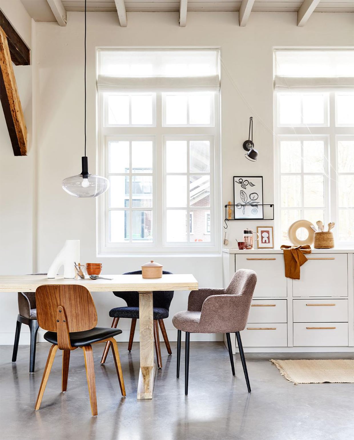 Mangohouten eettafel Deck in kleur Naturel, 200x90x78 cm (lxbxh) € 899,-, ook verkrijgbaar als ronde variant in kleur Clay, 120×78 cm ( Øxh) € 749,-. Linksachter: eetkamerstoel Scroll, met warmgrijze geweven stof, 53x50x76 cm (bxdxh) € 299,-. Rechtsachter: zwarte eetkamerstoel Cape, gemêleerde stof en hout, ook verkrijgbaar in blauw, 55x65x77 cm (bxdxh) € 199,-. Aan het hoofd: taupe eetkamerstoel Dining van geweven teddystof en metaal, ook verkrijgbaar in off white, 62x53x83 cm (bxdxh) € 249,-. Voor de tafel: walnoothouten eetkamerstoel Classic met PU lederen zitting, 48x50x81 cm (bxdxh) € 149,-. | m.m.v. vtwonen.be (hanglamp Alton 35 van Nordlux, object op tafel van vtwonen, kommen op tafel HKliving, koperen perculator Leopold Vienna, terrakleurige kop HKliving, artwork Hôtel Magique), hm.com (vloerkleed). Overig privébezit.