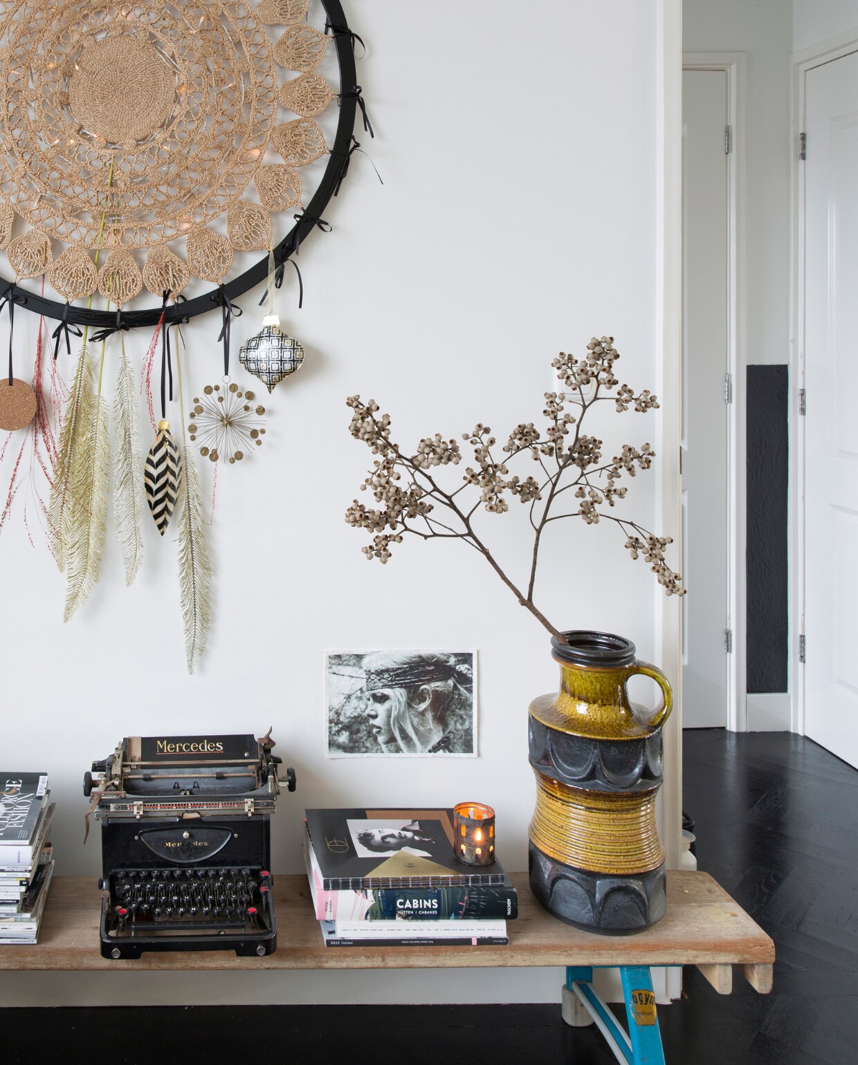 Dromenvanger zelfgemaakt. Foto Brigitte Bardot Goed in Stijl. Sidetable oude gymbank van de sportschool. V.l.n.r. tijdschriften Vogue,vtwonen, Elle Decoration, Soffa Magazine, typemachine Mercedes gevonden in container, mode-,interieur- en reisboeken, kaarsenhouder Stelling Wonen, vaas Berlijnse rommelmarkt, tak Floribundus. Visgraatvloer Van Dijk &amp; Ko, zelf zwart geschilderd en gelakt met producten van Sigma, muurverf RAL 9010 en matzwarte muurverf.