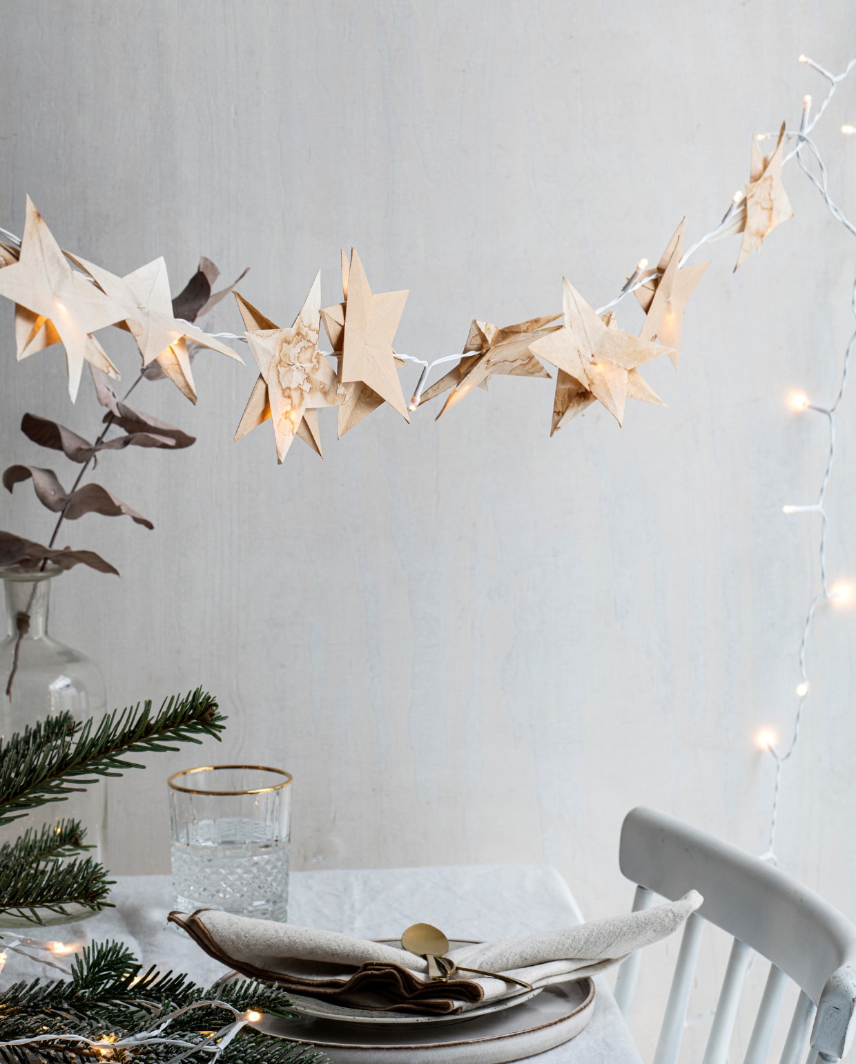 Houten eetkamerstoel, soortgelijke Lotta € 99,-. Gewassen wit linnen tafelkleed € 49,99, glas met reliëf en goudkleurige rand, soortgelijk vanaf € 5,99, porseleinen bord, bruin gespikkeld € 5,99, wit keramieken bord € 9,99, 3-delige bestekset € 9,99, katoenen servet, set van 2 € 7,99. Overig privébezit.