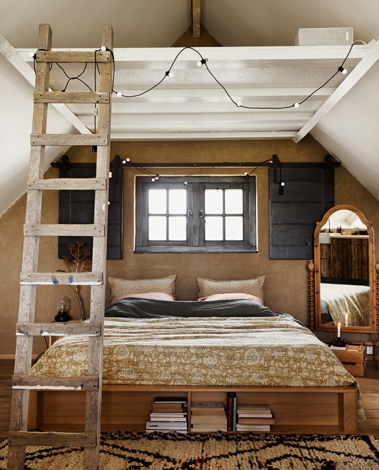 Bed Made. Ladder en spiegel Marktplaats. Sprei Indiase Khanta doek via Etsy. Kussensloop Zara Home. Lichtsnoeren Ikea. Vloerkleed The Souks. Muur afgewerkt met leemstuc. Overig onbekend.