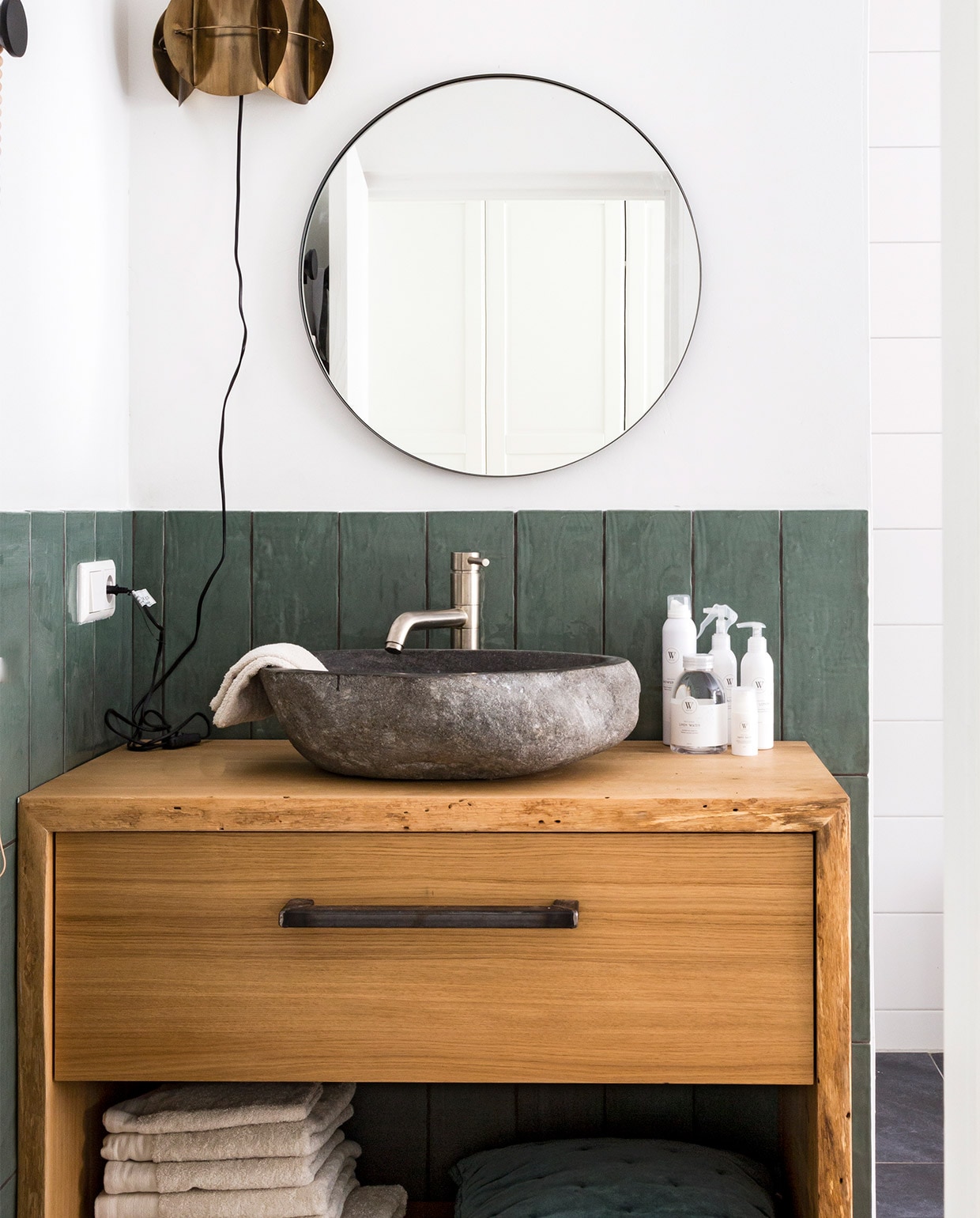 Wandtegels Mediterranea van vtwonen in kleur Army Green 134004, 13x40x1 cm per doos (19 stuks) € 59,75 (koltegels.nl). Spiegel MYME 60 € 99,-(bodilson.com). Wandlamp Corridor van Dutchbone € 66,- (vtwonen.nl). Handdoeken en gastendoekjes Soft Cotton vanaf € 6,95, handzeep, body mist en badschuim per stuk vanaf € 6,95 (walra.nl). Wastafel, waskom, kraan privébezit.