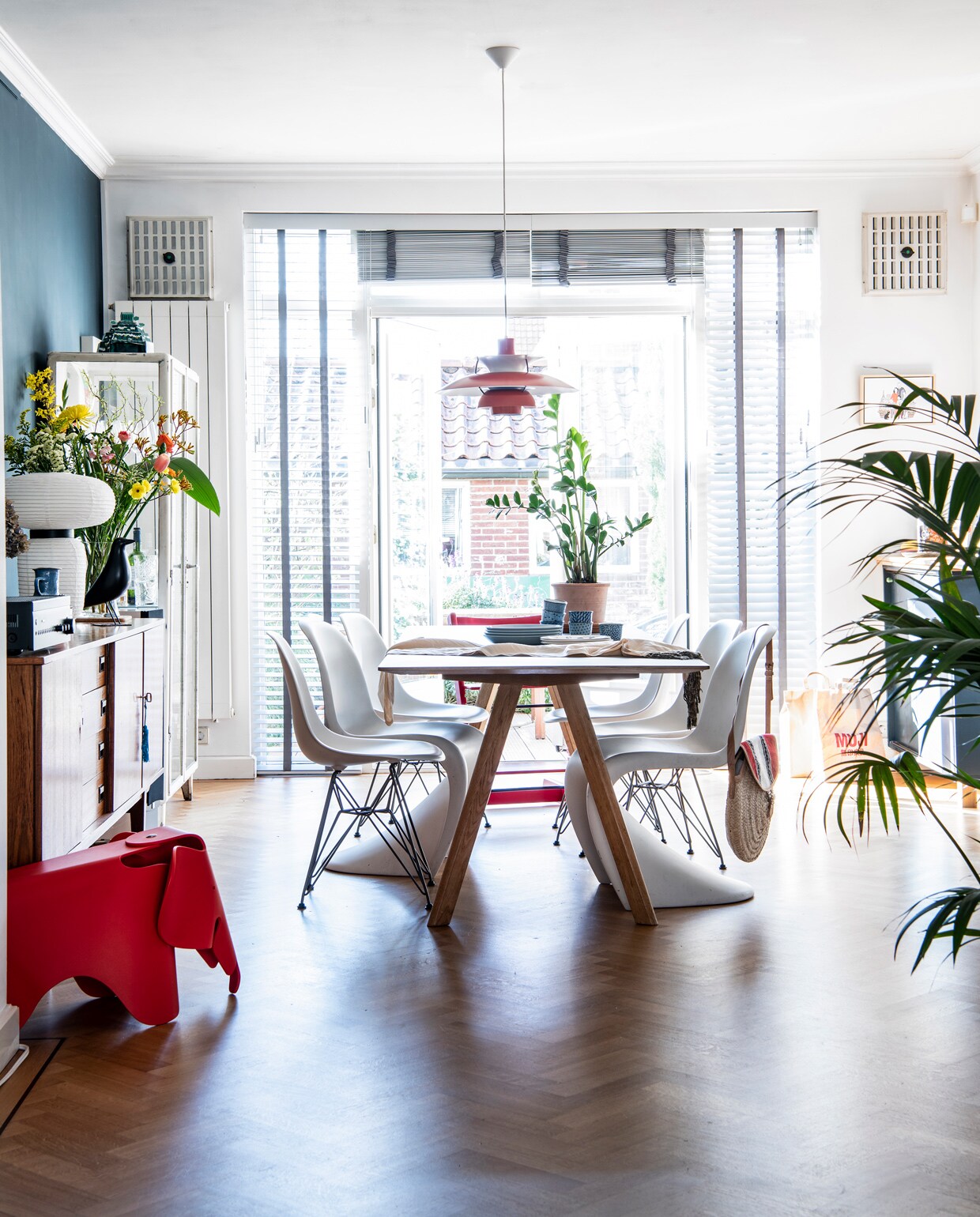 Muurverf links Ral 5008 van Engels Verf. De vloer lag al in het huis. Tafel CPH30 van Hay. Blauwe borden Iittala, witte borden met blauwe spetters Faye van Toogood, Japanse kopjes Shilla. Tas Dille &amp; Kamille. Panton-stoelen, Eames DSR-stoelen, Eames-olifantkruk en vogel House Bird van Vitra. Tripp Trapp-stoel Stokke. Vintage Lamp PH5 van Van Ons. Vintage kasten Loods 5. Witte lamp Formakami van &amp;Tradition. Plantenpot Arket, plant Sprinklr.