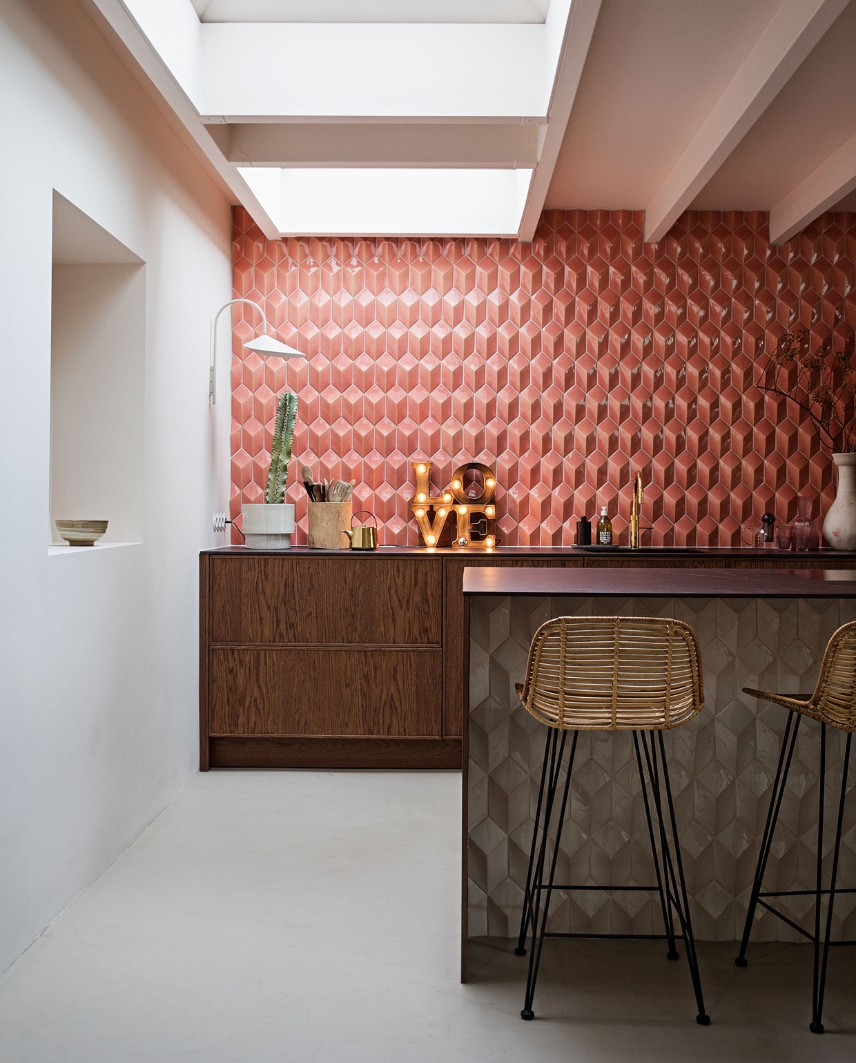 Barkrukken, theepot en kom in nis HKliving. Wandlamp Ferm Living. Love lamp Sissy-Boy Homeland. Tegels Constellation kleur Flamingo Baby via Quintalisque. Kraan Quooker. Houten pot Household Hardware. Bloempot H&amp;M Home. Planten Blóm. Overig herkomst onbekend.