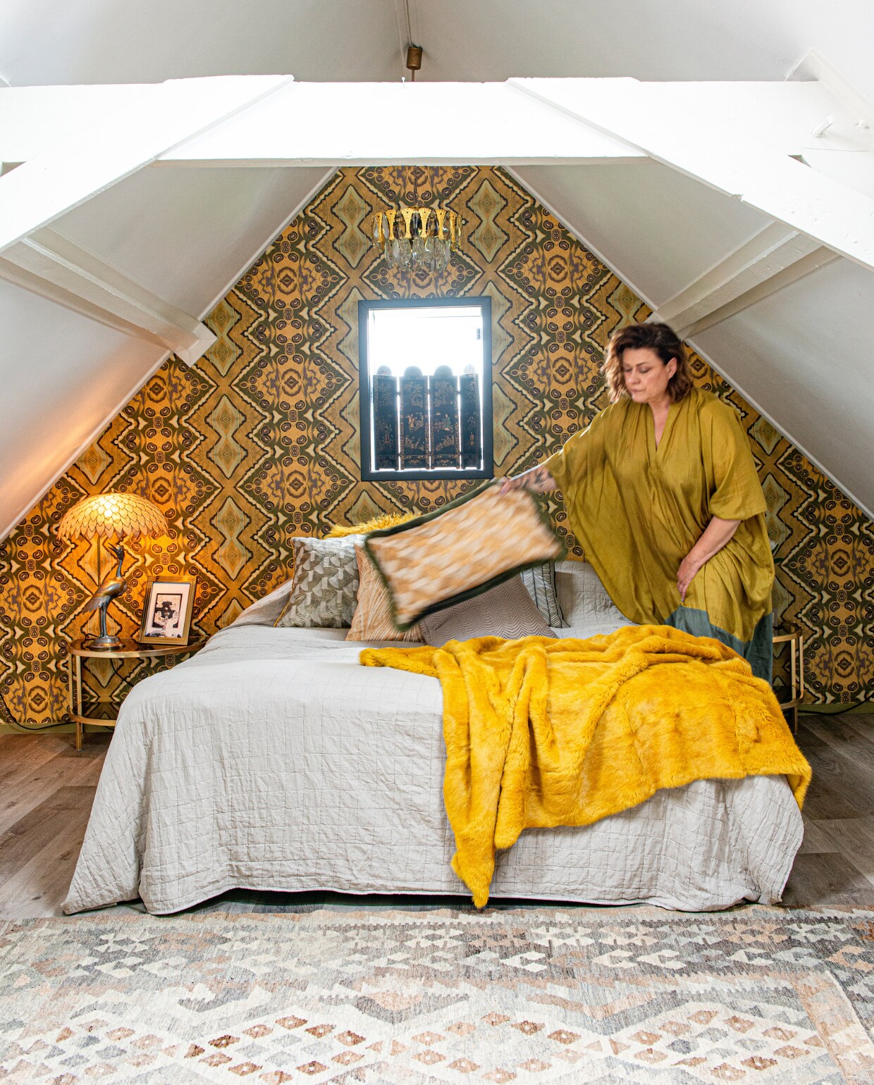 In het raam een mini-roomdivider uit een rommelwinkel, reiger tafellamp uit de jaren 60, half ovale nachttafels met getint glas en massief messing van onbekende fabrikant, fotolijst uit Duitsland, lamp van Gaetano Sciolari, kelim uit Afghanistan, behang Artwallcollection by Hanneke van de Pol, kussens Mippies, grijze sprei Jysk, gele sprei van lamsvacht herkomst onbekend.