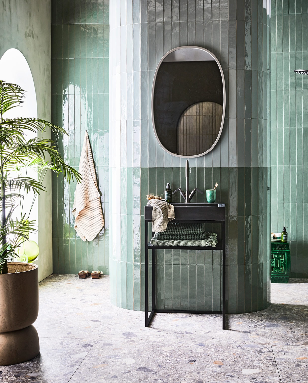 kleur Seagreen, glans, 6,5×40 cm. Donkere wandtegel Marrakesh, kleur Army Green, glans, 6,5×40 cm . Vloertegel Composite, kleur Multicolor, 120×120 cm. Betonnen wastafel Tank met kraangat, kleur Concrete Black, 10x60x46 cm (hxbxd). Metalen frame, kleur Black, 81x60x45 cm (hxb). Planchet Frame, kleur Oak Black, 6×41 cm. Wastafelkraan Grip, kleur Black Steel, met twee hendels. M.m.v. vtwonen.nl (spiegel Umbra, badlakens van Marc O’Polo), nordal.eu (plantenpot), polspotten.nl (keramieken kruk), bungalow.dk (beker, lichtgroene wafeldoek, grijze gastendoek), hm.com (handzeep Meraki).