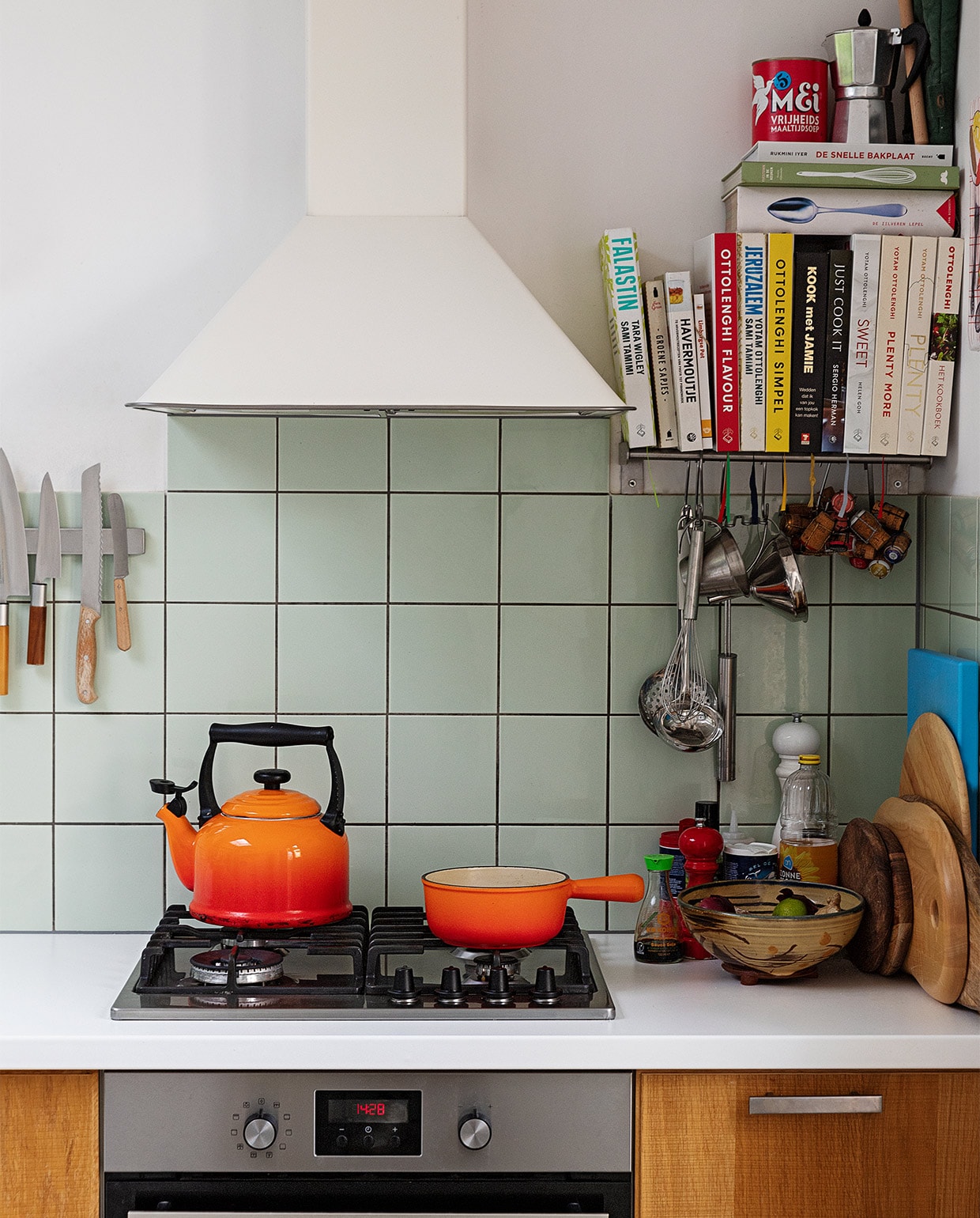 Oranje fluitketel en pan Le Creuset. Messen Suncraft, Opinel en Dille &amp; Kamille. Kookboeken Ottolenghi, Jamie Oliver, Sergio Herman, Yvestown in de keuken, De Zilveren Lepel. Snijplanken Hay, Ikea en Serax. Peper- en zoutmolen Peugeot. Soeplepel Brabantia. Hangend rvs keukengerei Dille &amp; Kamille. Percolator tweedehands. Schaaltje van een pottenbakkersmarkt. Afzuigkap en oven Ikea. Ovenhandschoen Kook. Pollepel Kookhuis aan de Maes.