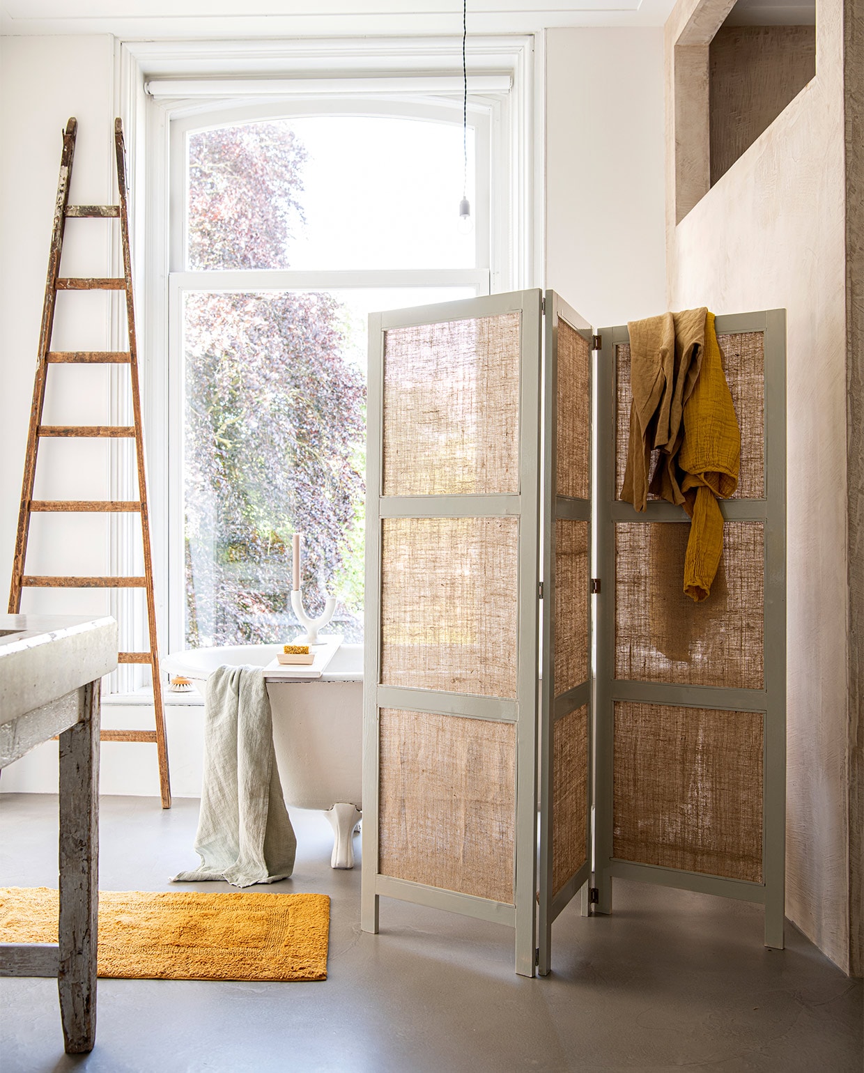 Jute kamerscherm DIY uit vtwonen special 05-2022. Ook zelf maken? Bestel de DIY special hier.,  Katoenen badmat, 60×100 cm € 49,95, groene linnen wafelhanddoek € 39,95 (yumeko.nl). Houten zeepschaal Hinoki € 18,-, badborstel van Iris Hantverk € 30,- (thefinestore.com). Kandelaar van Urban Nature Culture € 39,95 (zaanschfaamwebshop.nl). Zeep van Kusala € 7,95, okergele linnen top € 50,- (atelierhop.com). Jurk Nina in kleur Sunflower Yellow € 85,- (lidor.nl). Overig privébezit.