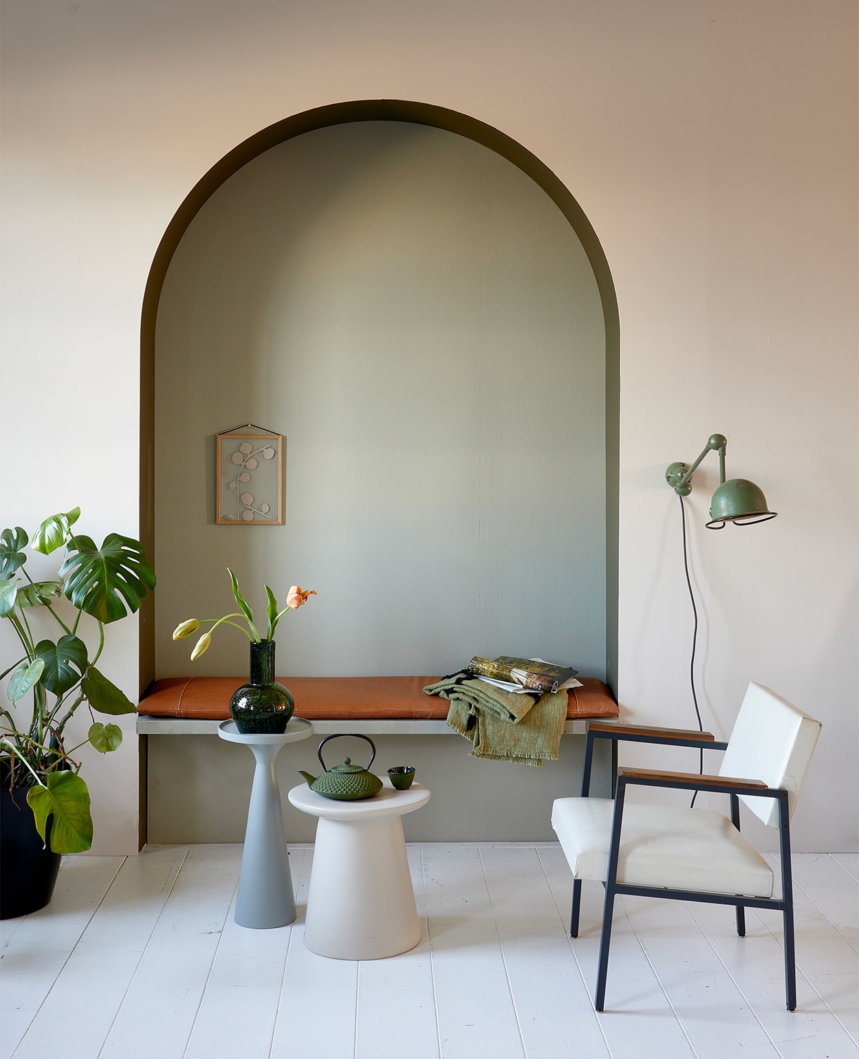 Muurverf krijtlook mat van vtwonen, kleur op de wand Linen, in boog Camouflage, op achterwand Stone, per liter € 14,20 (karwei.nl). Leren kussen op bank, 40x160x5 cm (bxlxh) € 339,- (nahka.nl). Vintage stoel met witte kunstleren bekleding € 175,-, Jieldé lamp aan de wand € 375,- (neeflouis.nl). Groene plaid, 130×170 cm € 74,95, aardewerken bijzettafel, 40×43 cm (Øxh) € 249,-, groene glazen vaas, 19×24 cm (Øxh) € 39,95 (hkliving.nl). Aluminium bijzettafel Floss, 28×56 (Øxh) € 110,- (zuiver.com). Gietijzeren theepot Xilin € 35,05 en gietijzeren kom Xilin van Bredemeijer, per 2 € 17,85 (vtwonen.nl). Aan de wand in nis: eikenhouten lijst Moebe, A4 € 44,- (nordicnest.nl). Overig privébezit.