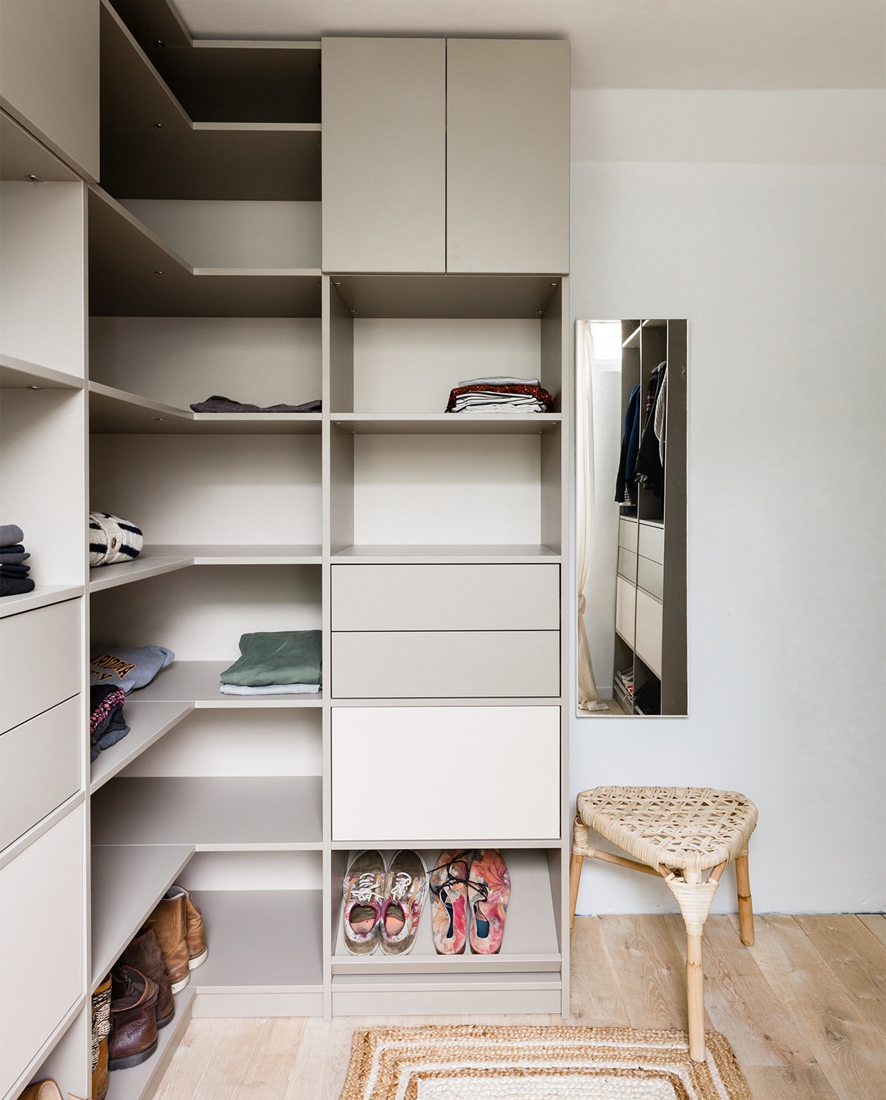 Op maat gemaakte kast in kleuren Zandbeige U156-9 en Natural Grey U115, prijs op aanvraag (woninginrichting-aanhuis.nl). Plafondspot Nymåne € 39,95, rotan kruk Tänkvärd € 39,95 (ikea.nl). Vloerkleed loper jute natural € 99,45 (rocaflor.nl). Gordijnen Gathered Natural, per stuk € 49,- (lidor.nl). Spiegel € 9,99 (xenos.nl). Rek voor surfplanken zelfgemaakt. Surfplanken, kleding, gordijnroedes privébezit.