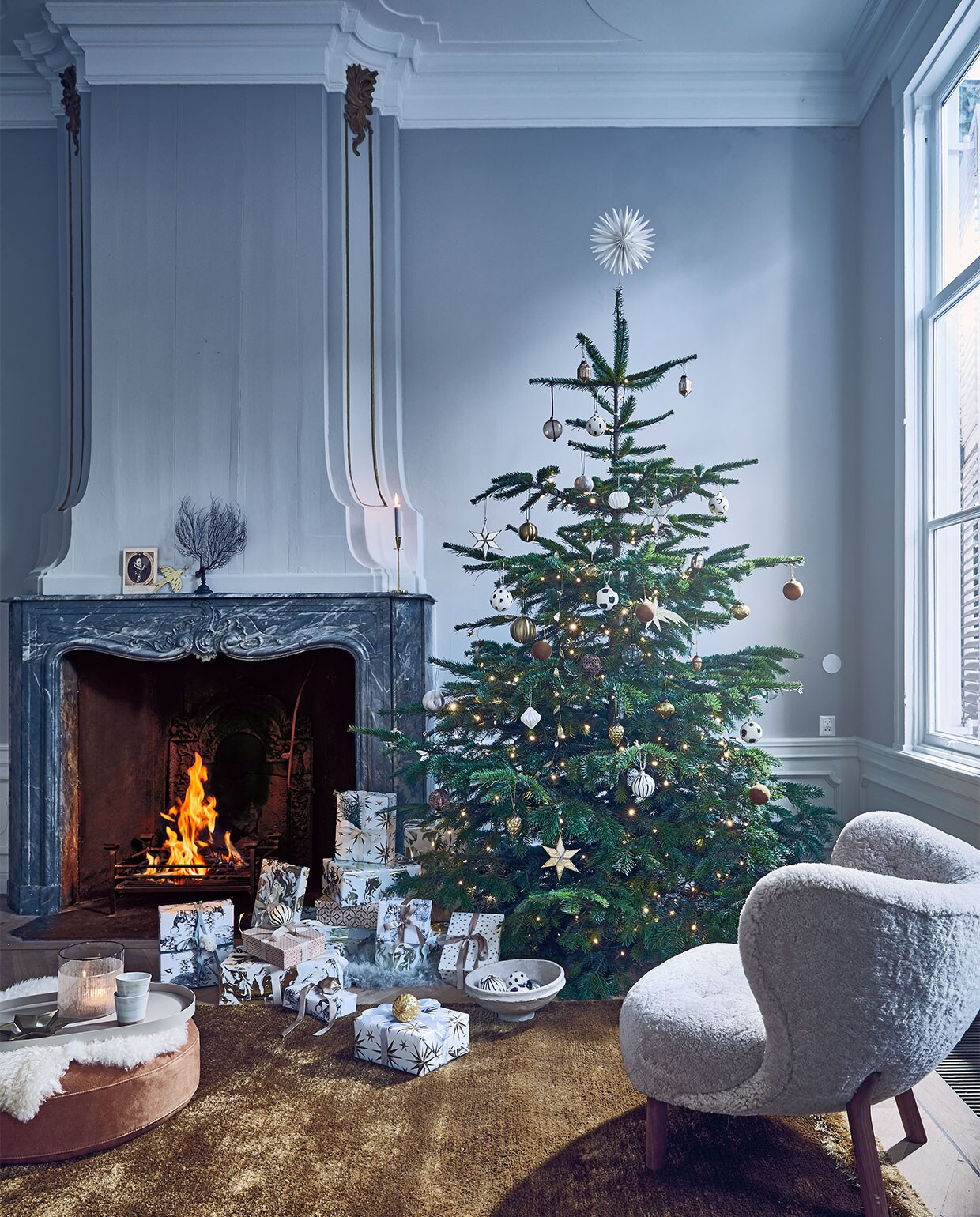 Kerstlampjes diamantverlichting warm wit van Lumineo, 29,9 m € 34,95, vloerkleed Nami van Bolia, 170×240 cm € 740,-, suède poef Time van Bloomingville € 208,99, dienblad van Serax 53×31,5 cm € 66,-, schapenvacht van Weltevree € 79,-, espressomokken Grid van Broste Copenhagen 0,15 l per stuk € 9,99 (vtwonen.be). Fauteuil bekleed met schapenvacht van &amp;Tradition, 81x83x75 cm (bxdxh) € 4534,- (homestede.nl). Glazen windlicht € 19,99, papier-maché schaal € 38,50, transparante glazen ballen € 7,60, ballen met veertjes € 4,50 (nordal.eu). Handbeschilderde ballen met strepen en stippen € 19,- (fermliving.com). Spiegelsterren € 5,99, eikels en diamantvormige glazen ornamenten per stuk € 2,99 (sissy-boy.com). Gouden vallende sterren per stuk € 10,-, gouden vredesduif € 13,-, guirlande met gouden blaadjes € 20,-, stervormige piek € 35,-, gedecoreerde dozen set van 3 € 58,- (bungalow.dk). Okergele fluwelen kerstballen set van 2 € 5,99, wit-goud-marmer pakpapier € 3,99, pakpapier met sterren € 3,99, pakpapier met zwart-wit bos € 3,99, satijnlint € 2,99 (hm.com). Overig privébezit.