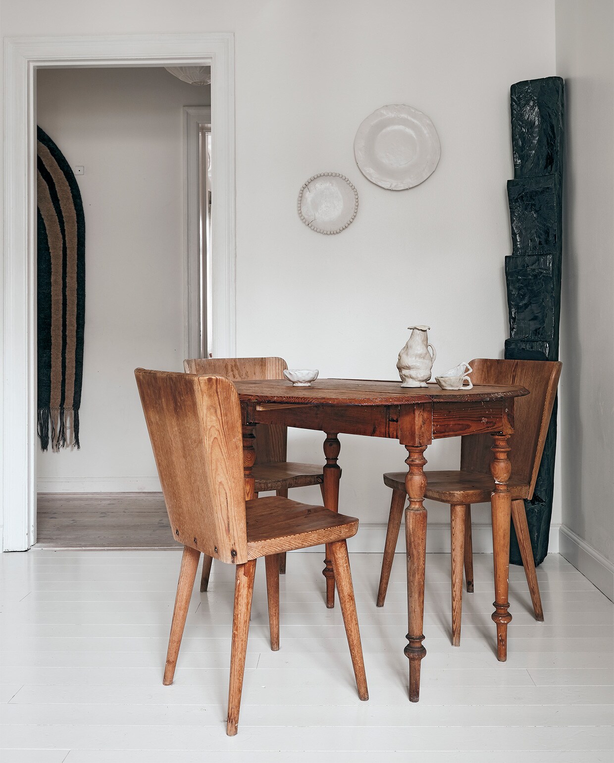 Borden aan de muur en keramiek op tafel gemaakt door Ellen. Houten object winkeldecoratie By Malene Birger, Zweedse tafel vintage, vintage stoelen Gøran Malmvall. Aan de muur in de gang kleed Cappelen Dimyr no.06,