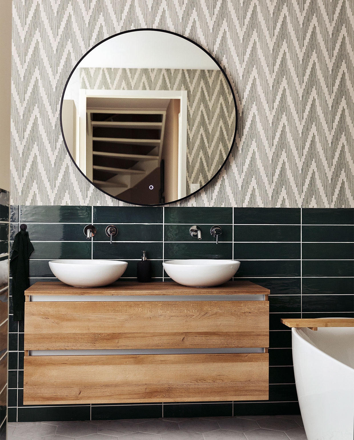 Badkamerkast Unihopper. Wastafelkommen Solid Surface. Kranen en vrijstaand bad ADW. Spiegel Best Design. Tegels Sartoria. Behang BN Walls. Kleed H&amp;M Home.