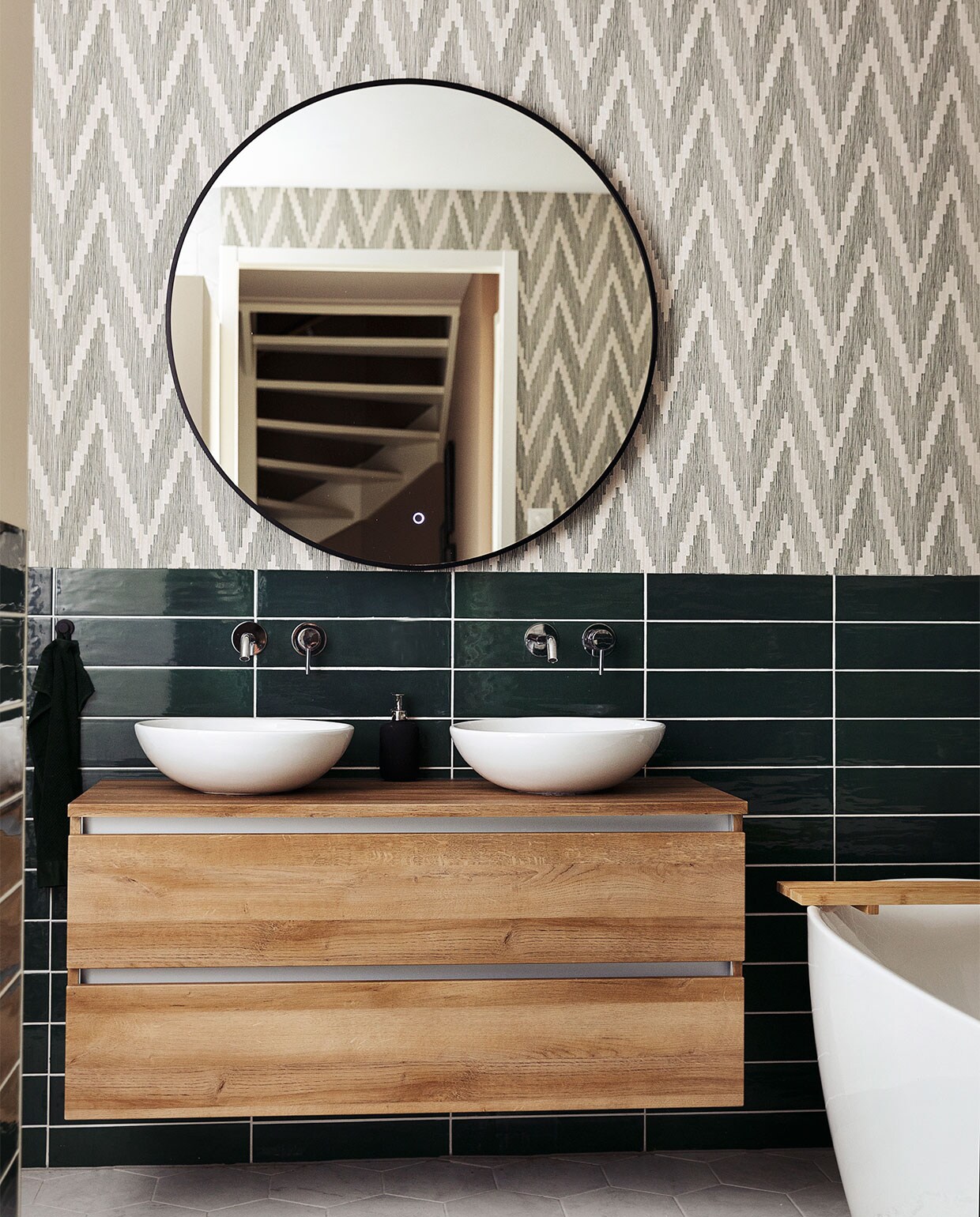 Badkamerkast Unihopper. Wastafelkommen Solid Surface. Kranen en vrijstaand bad ADW. Spiegel Best Design. Tegels Sartoria. Behang BN Walls. Kleed H&amp;M Home.