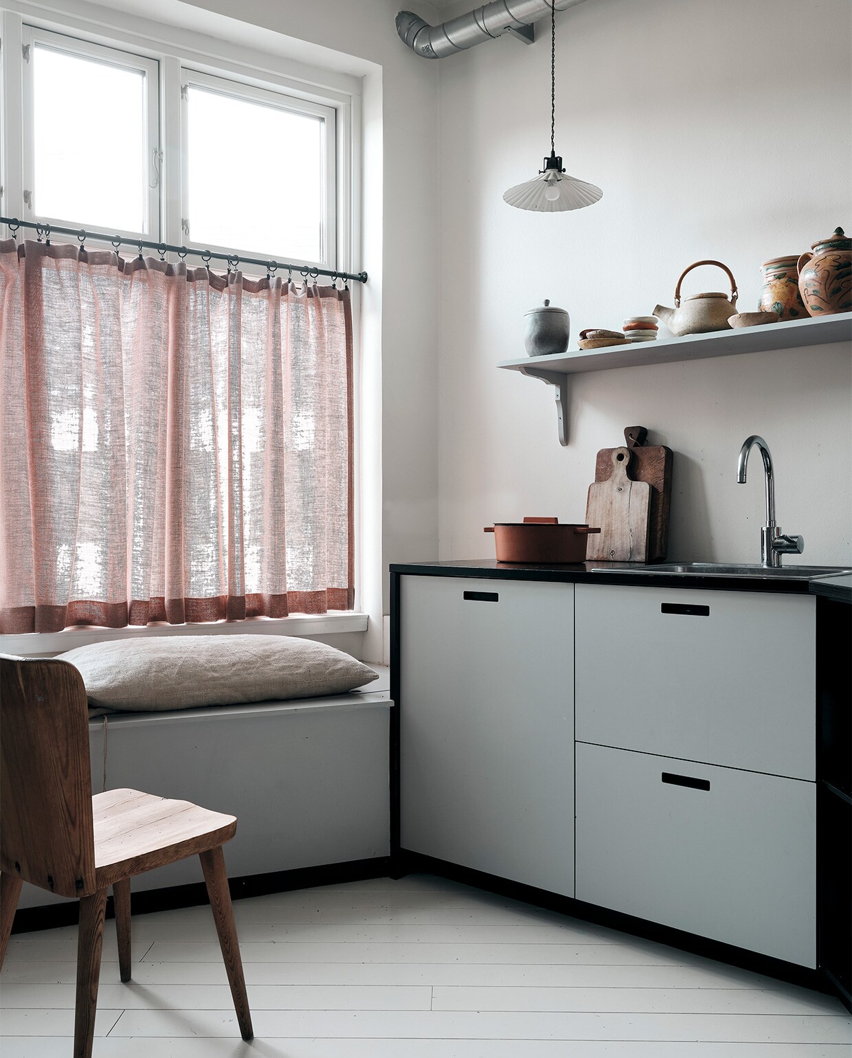 Keuken op maat gemaakt in Kopenhagen. Vintage houten snijplanken en pan, gordijnen Astrid Textiles. Op een antieke plank keramiek uit Sicilië, handgemaakt door Ellen en vondsten van rommelmarkten. Vintage lampje, vintage stoel Gøran Malmvall.
