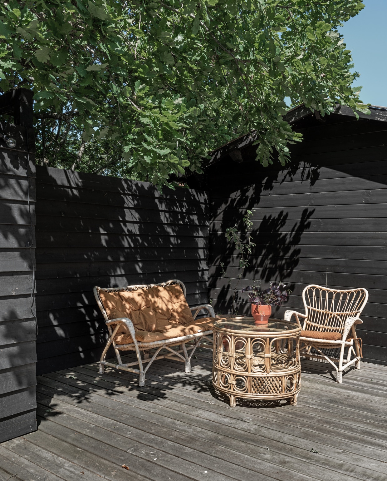 Rotan bank, fauteuil en salontafel rommelmarkt. Kussens Madam Stoltz. Plantenpot Skagerak.