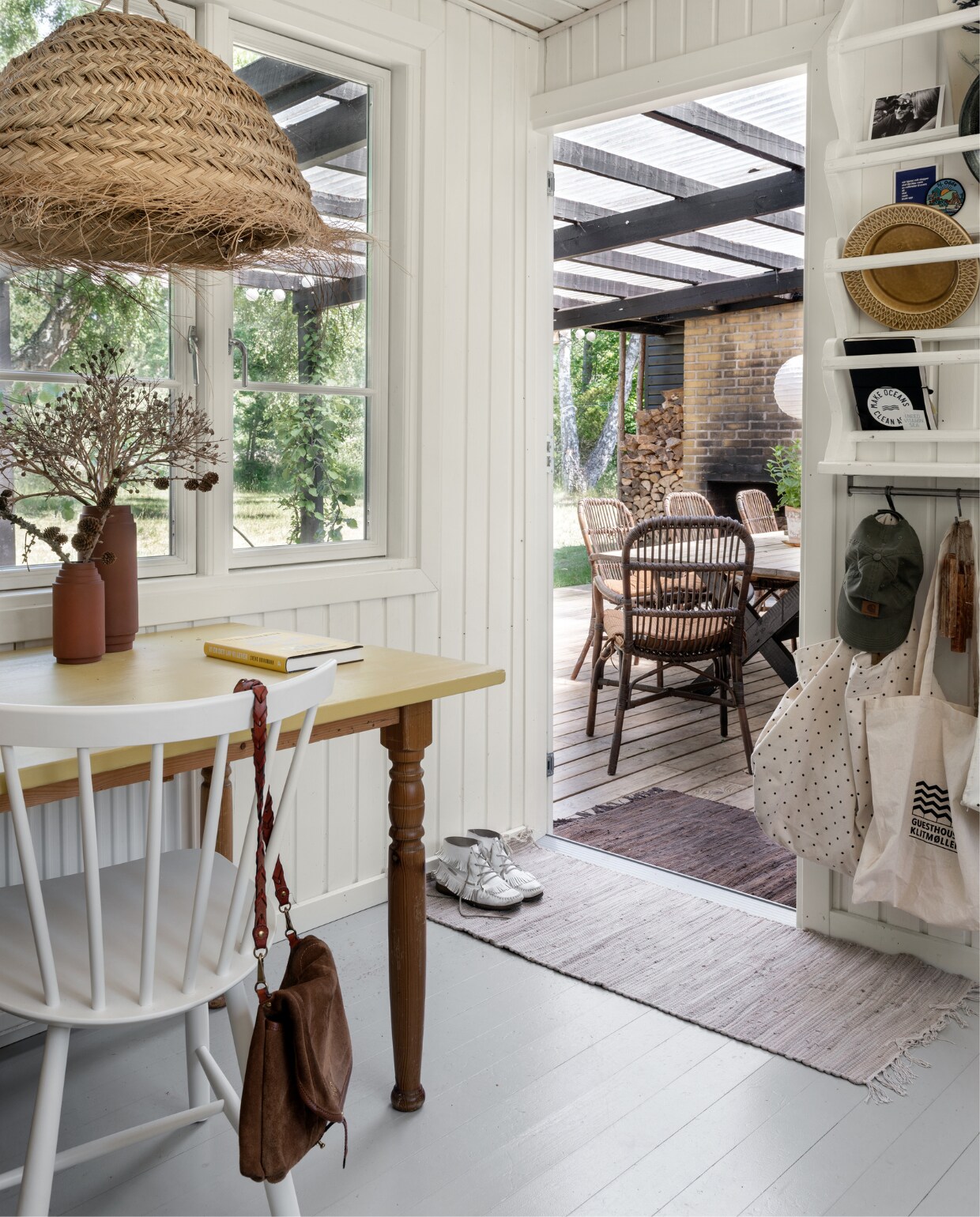 De tafel is nog van Rikke,s ouders geweest, waarvan Rikke het blad geel schilderde. Vaasjes rommelmarkt. Stoelen J46 FDB Møbler. Schoudertas Jerome Dreyfuss. Het witgeverfde bordenrek is zelfgemaakt, met daarin o.a. kaarten, vintage keramiek en tassen en een waterfles van Moshi Moshi Mind. Strolamp Madam Stoltz. Kleden Søstrene Grene.