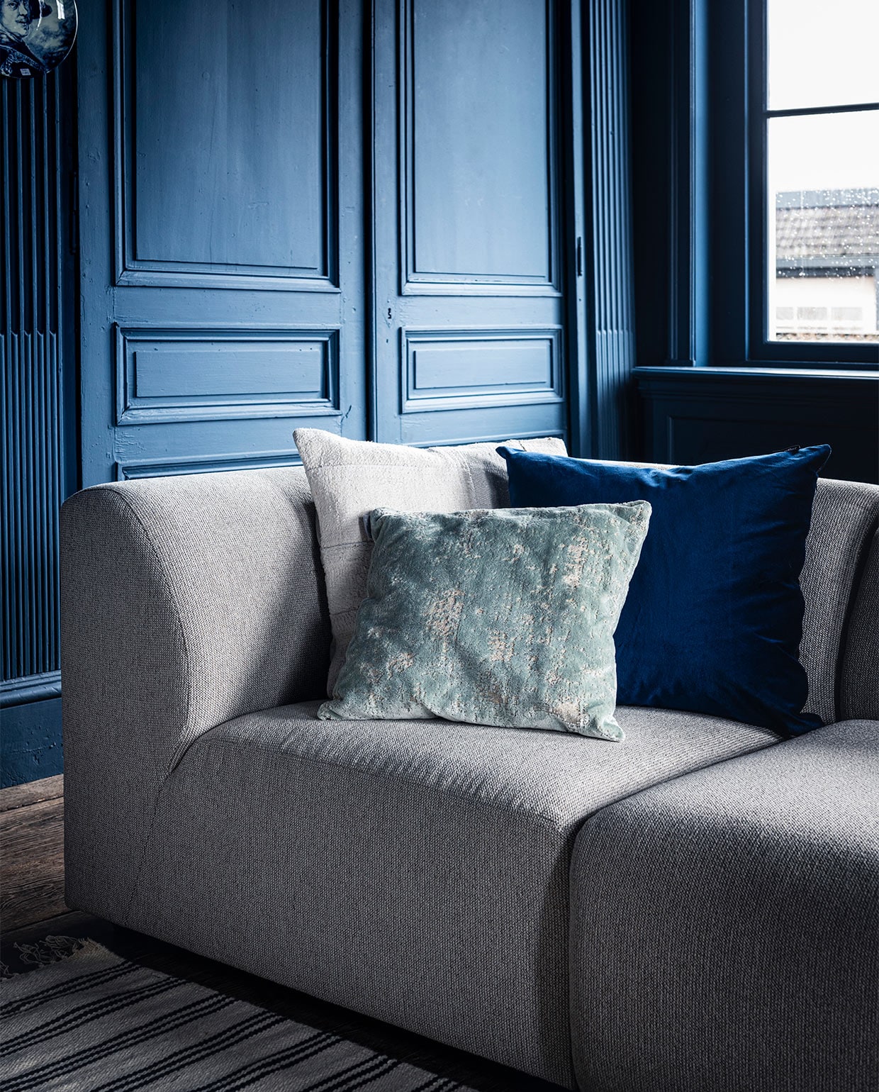 Bank Jax van HKliving, element vanaf € 499,- (vtwonen.nl). Wit kussen van Mrs.me € 99,- (homestede.nl). Blauw kussen € 49,-, ecru kussen € 49,-(couleurlocale.eu).