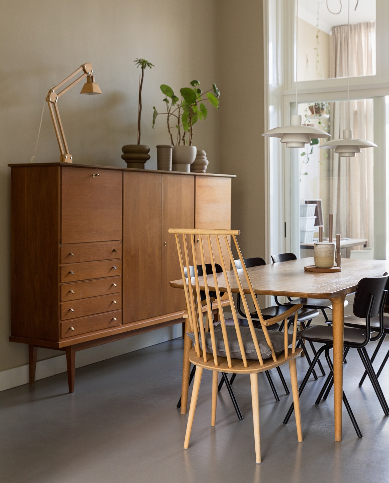 Muurkleur GN 080-08. Vintage Deense kast Marktplaats. Eettafel Fawn van Gazzda. Houten stoel Hay. Eettafelstoelen Dykmeyer via De Machinekamer. Tafellamp gekocht in Kopenhagen. Vintage plafondlampen PH4/3 van Louis Poulsen. Potten Nørd Conceptstore en rommelmarkt, planten via Nørd Conceptstore. Overig onbekend.