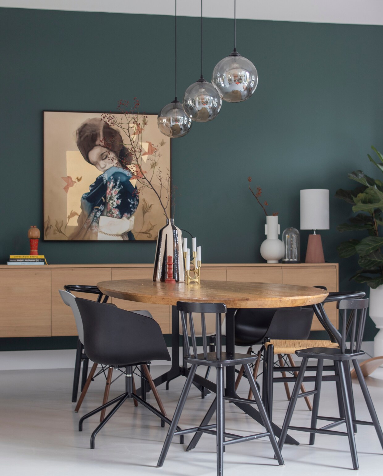 Muurverf Frivool van Histor, tafelblad Marktplaats met onderstel gemaakt door Vitriwand, rieten stoelen en boekenstandaard Loods 5, kinderstoelen Ikea, kuipstoelen Mobelaris, kunstwerk Chris Luka, hanglampen Wonenmetlef, tafellamp zelf samengesteld, dressoir gemaakt door Mh Design Meubelen, kaarsen en vaas op tafel Zara Home, witte vaas HKliving, balansbord Wobbel, kist vtwonen. Overig onbekend.