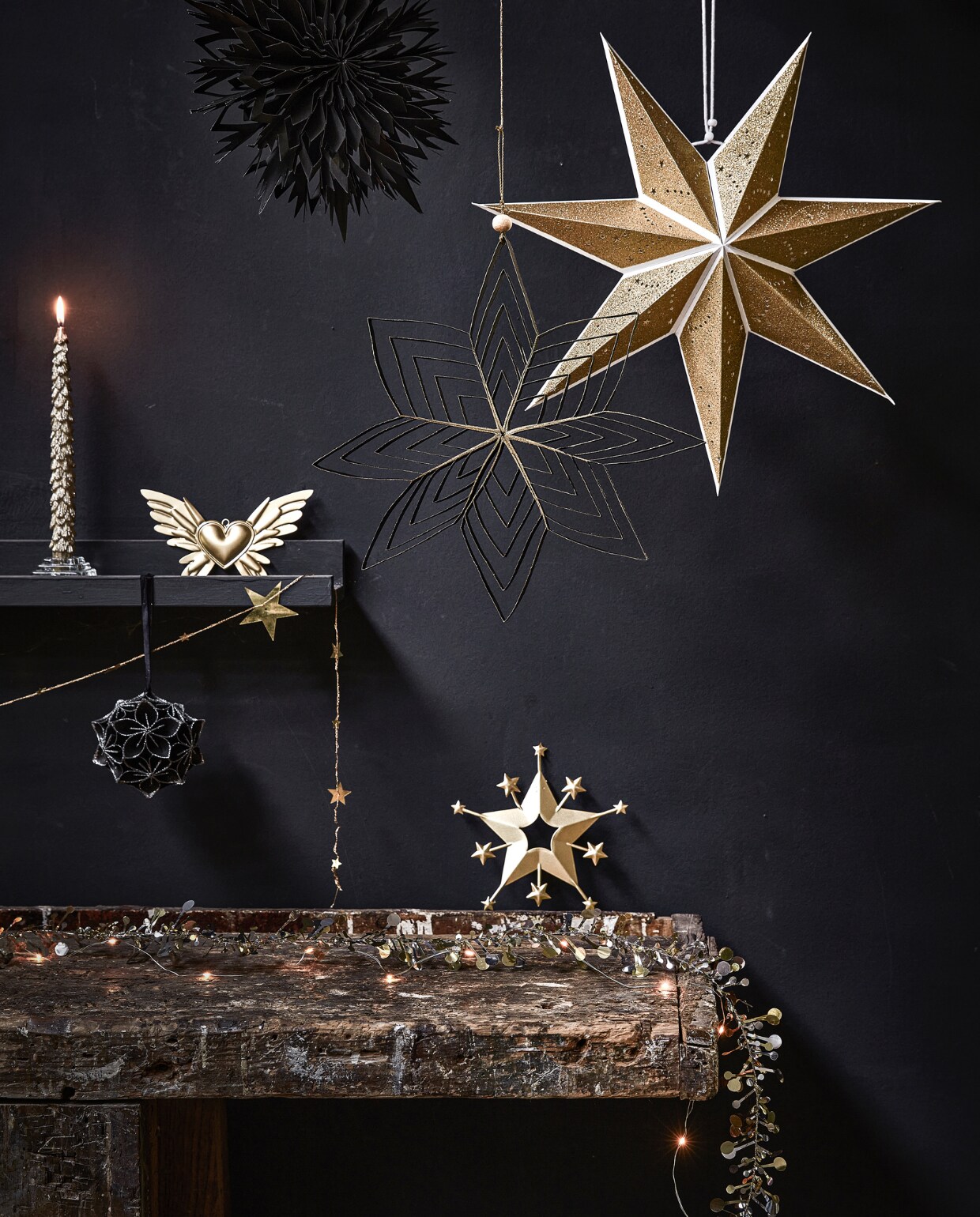 Zwarte papieren waaier, 30×7 cm (Øxd) € 3,99, zwarte papieren ster, 30×2 cm (Øxd) € 3,29 (ook verkrijgbaar in goud en wit), goudkleurige papieren ster, 70×19 cm (Øxd) € 9,99, goudkleurige kaars met glitter, per 2 € 6,99, goudkleurige metalen decoratie vleugels met hart, 18×10 cm (bxh) € 4,99, goudkleurige metalen slinger met sterren, 210 cm (l) € 3,49, zwart papieren ornament bloem met glitter, 10 cm (Ø) € 5,99, goudkleurige ster, 18×17 cm (hxb) € 7,29, goud- en zilverkleurige slinger met sterren en bolletjes, 120 cm (l) € 7,99.