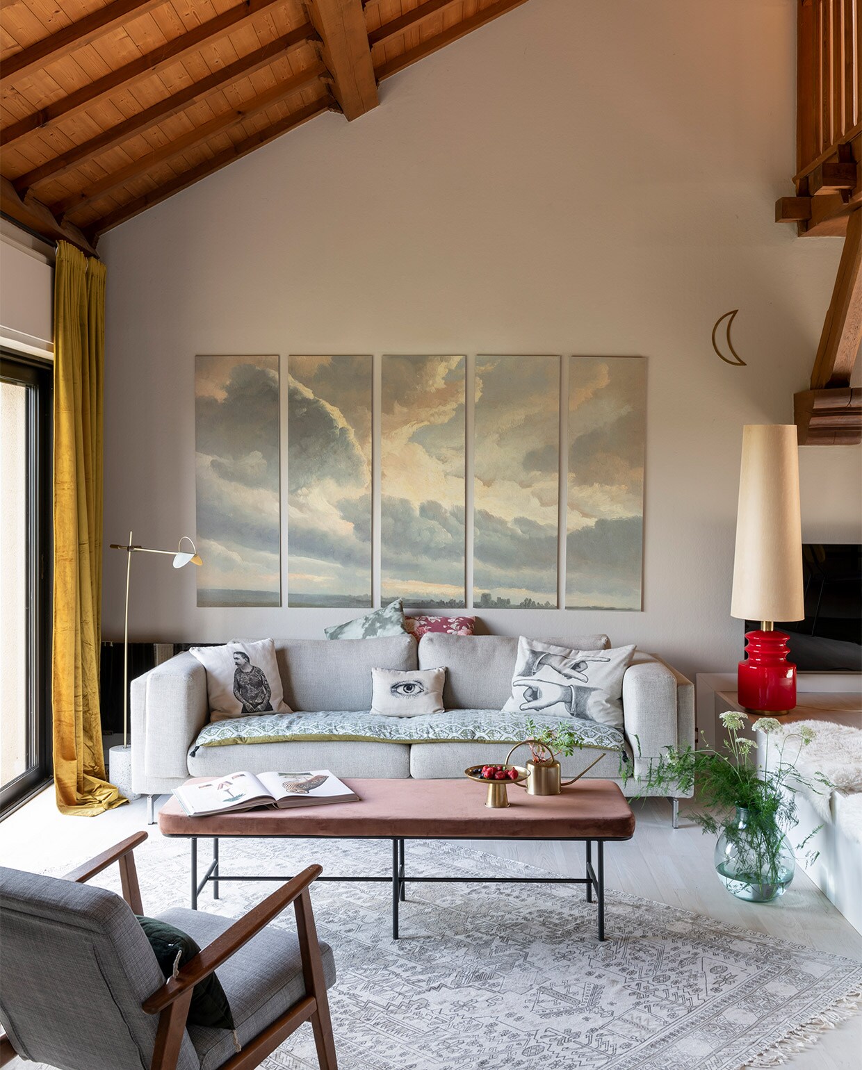 Schilderijen Sunset Clouds van Dominotiers, bank en fauteuils Ikea, salontafel House Doctor, rode lamp via La Brocante des Morues, kussens van Vanillafly, Le Monde Sauvage en Héritage Studio. Deken op bank Harmony Textile, vloerkleed HKliving, vloerlamp Bolia, gordijnen zelfgemaakt met stof van Nobilis, vachtjes Fab Design, maandecoratie Les Petits Bohemes, gieter en plateau H&amp;M Home, vaas Casa.