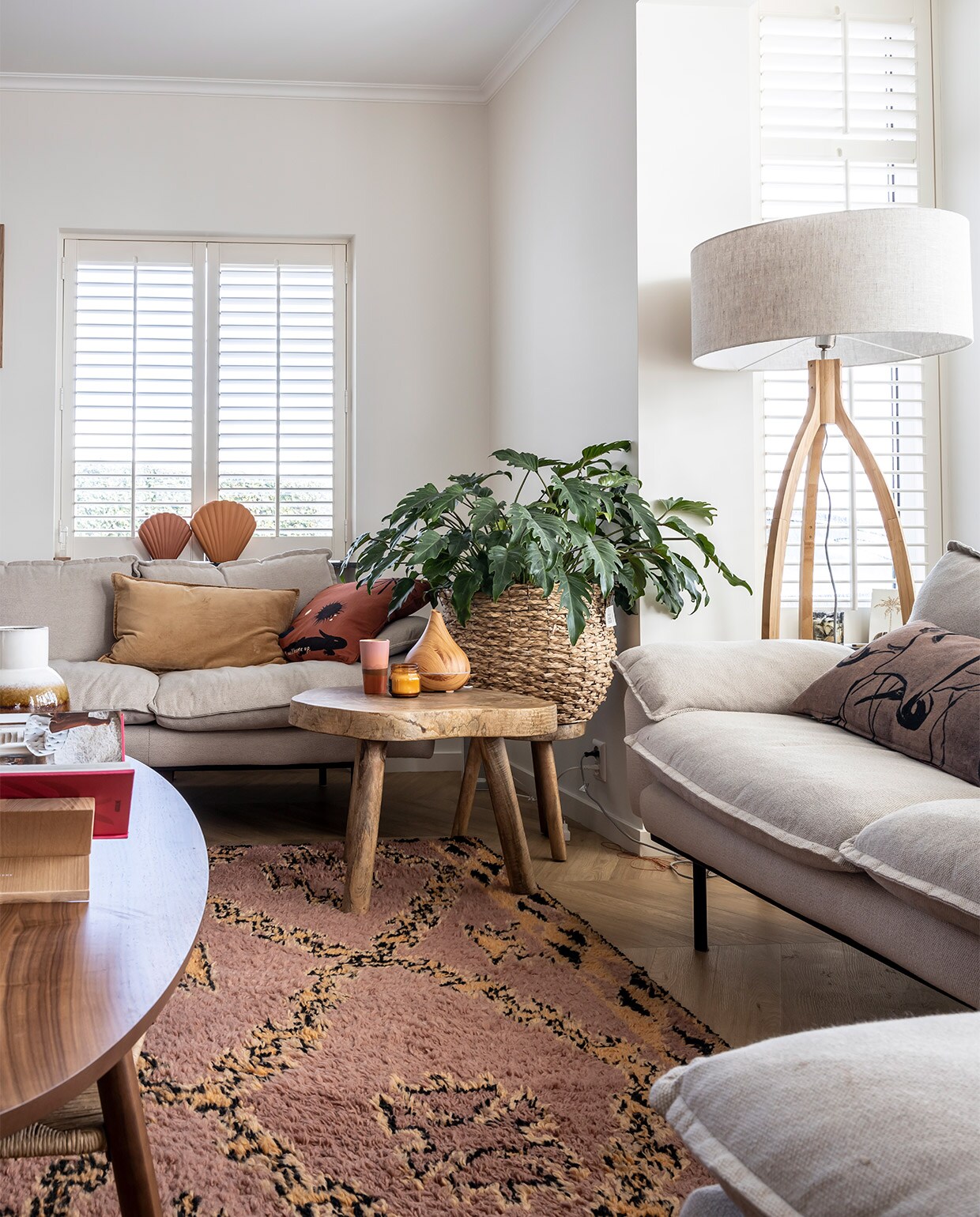 Lijsten Desenio, foto’s Profotonet, banken, kussens, schelpenvazen, vloerkleed, plaid en kruk HKliving. Salontafel Ikea Stockholm-lijn, vaas op tafel Zara Home, lamp It’s About Romi. Boekenstandaard onbekend, mand tuincentrum, mok HKliving, diffuser Geurwolkje. Shutters Veneta.
