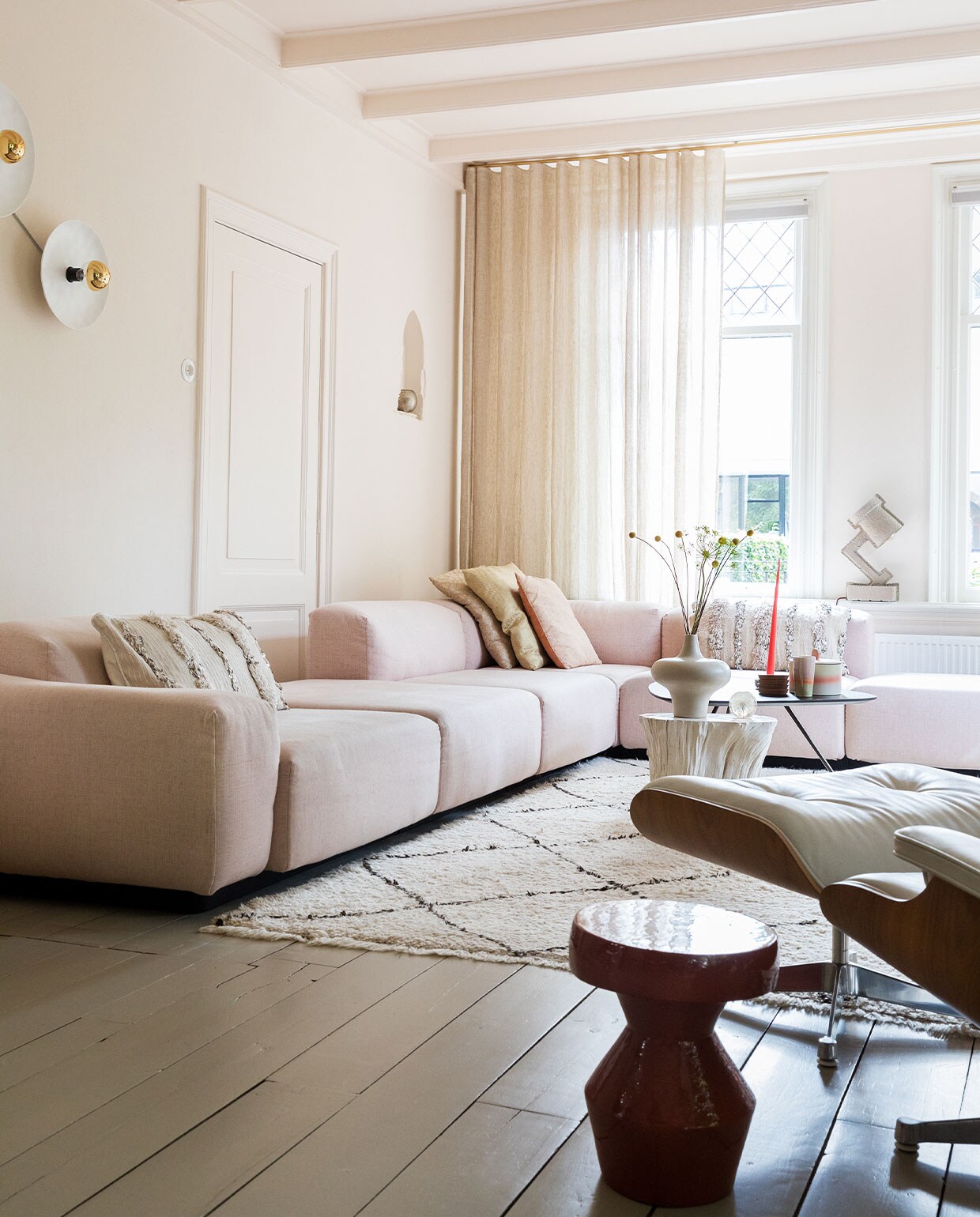 Bank Soft modular van Jasper Morrison en stoel Eames via Vitra. Vloerkleed en kussens links en rechts Household Hardware. Kussens midden Blooming Interior. Witte bijzettafel en vaas van Pols Potten via Wim van Assem bloembinderij. Zwarte bijzettafel Leolux en bijzettafel voorgrond via Eijerkamp.Wanden, deur, plafond kleur Julie’s Dream van Little Greene. Vloer kleur Brown Wood van Vestingh Paint. Papier-maché lamp Tradition via Loods 5. Gordijnen Van den Bosch Interieurstoffen. Messing railroede Corpus van Interstil. Presse papier Hafod Grange. Wandlampen vtwonen. Theebeker en koektrommel HKliving. Onderzetters Ikea. Kaars Ester &amp; Erik.