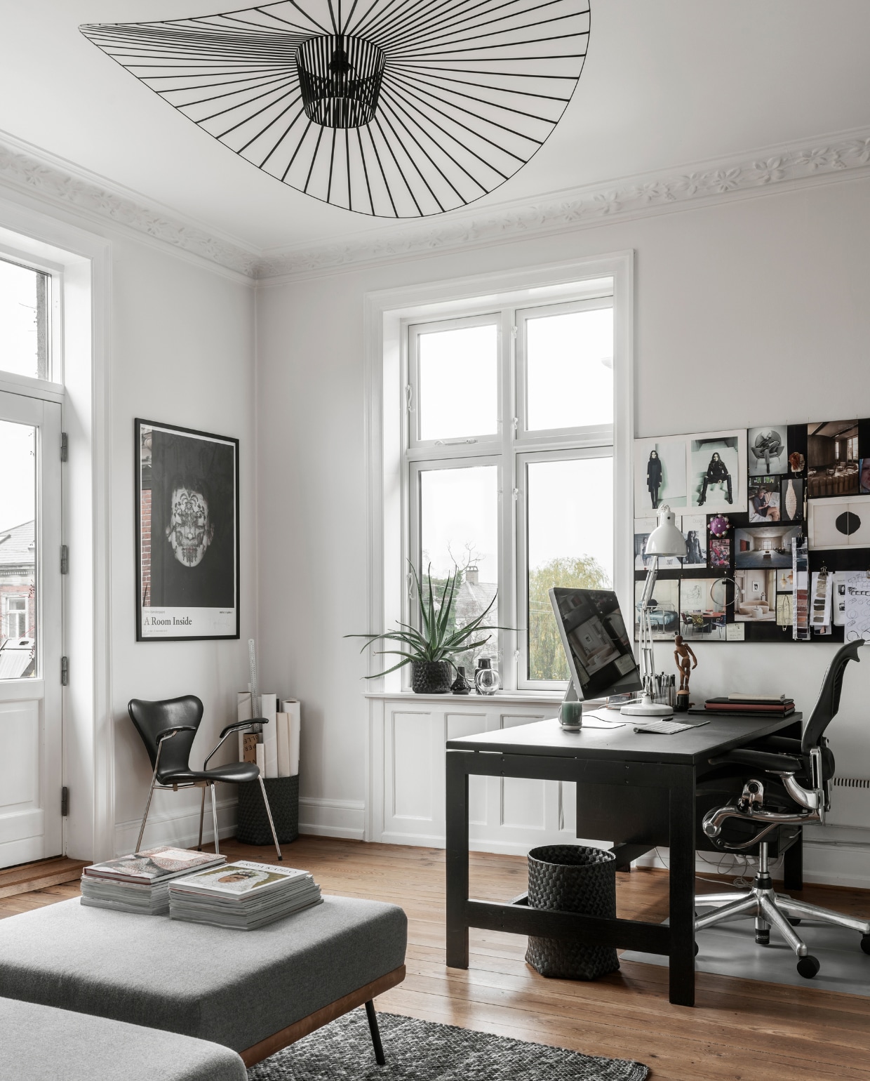 Daybed REM met bijpassende hocker van Sofacompany, Series 7 stoel door Arne Jacobsen, ingelijste poster met werk van fotograaf Trine Søndergaard, tweedehands bureau dat meerdere malen zwart is geverfd, bureaustoel ontworpen door Donald Chadwick en William Stump, plafondlamp Vertigo ontworpen door Constance Guisset, tweedehands bureaulamp Louis Poulsen. Moodboard met diverse knipsels, foto’s en kleurkaarten.
