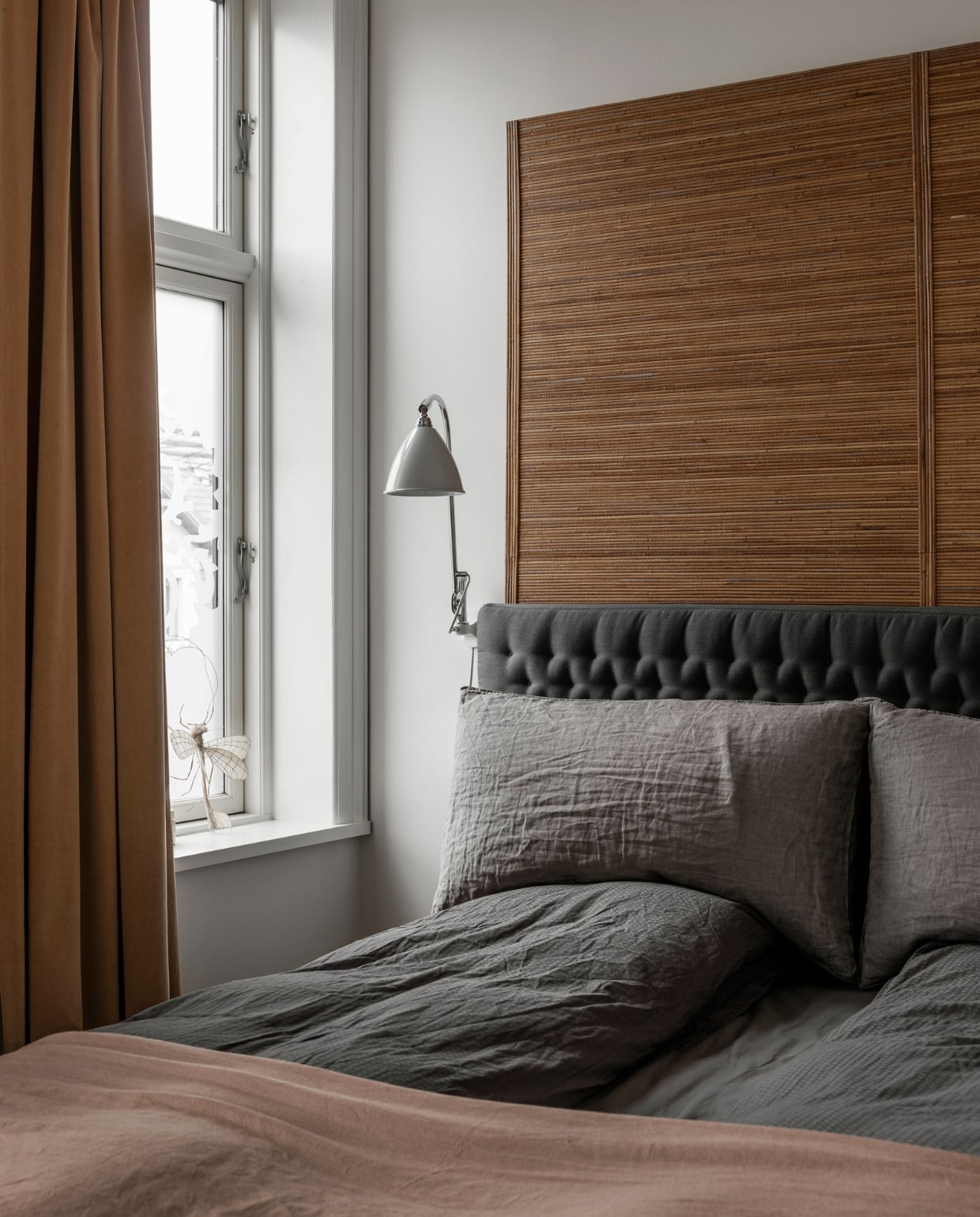 Bed met grijse headboard Dux, bedlinnen Facet ontworpen door Line’s moeder voor Georg Jensen Damask, gordijnen en caramelkleurige achterwand bed zelfgemaakt, witte lamp Bestlight.
