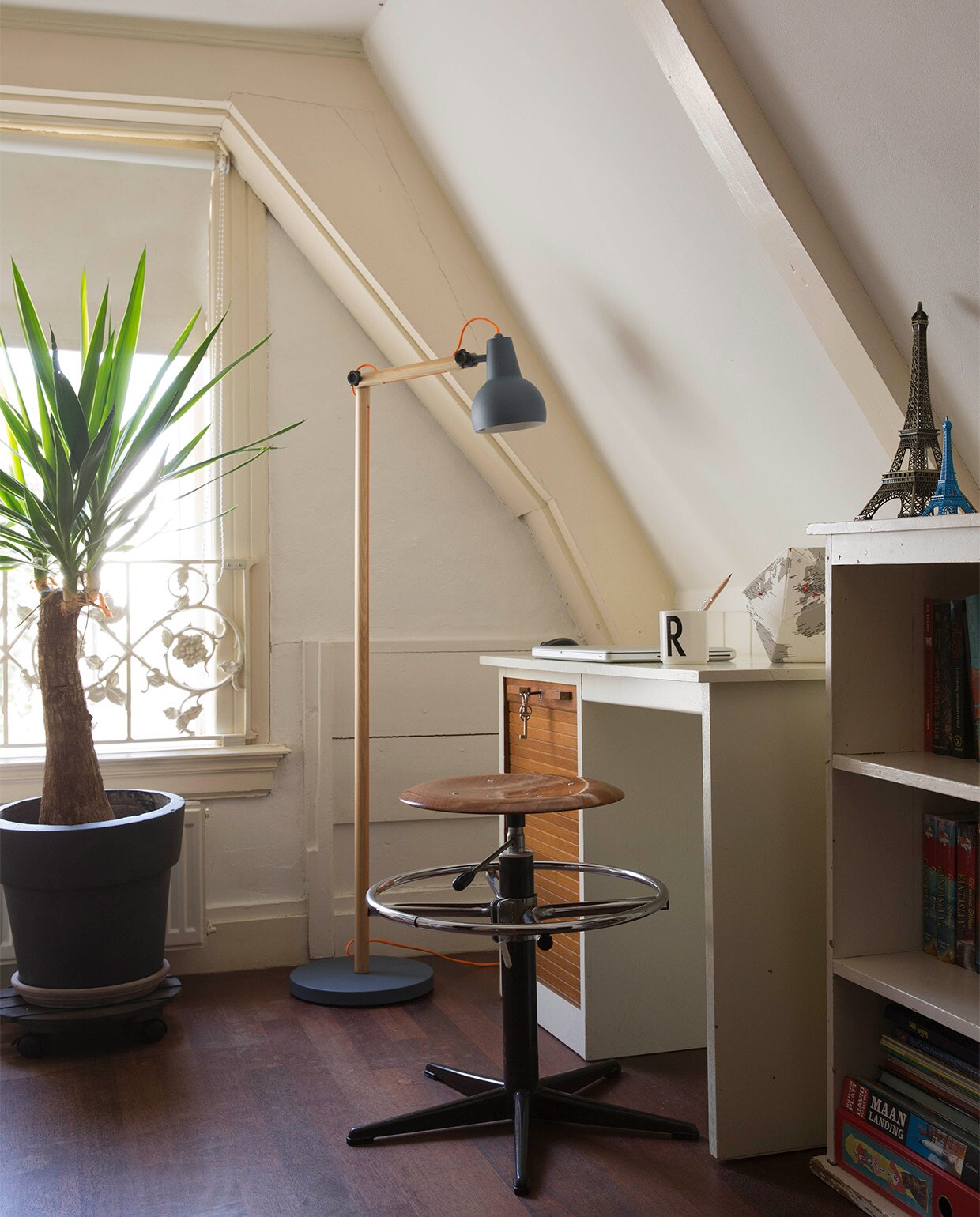 Het bureau, het kastje en de stoel zijn erfstukken. Beker van Design Letters, ontworpen door architect Arne Jacobsen, gekocht bij de Bijenkorf. Plant Yucca. Staande lamp Study (grijs) van Zuiver. Verduisterend rolgordijn Hema.
