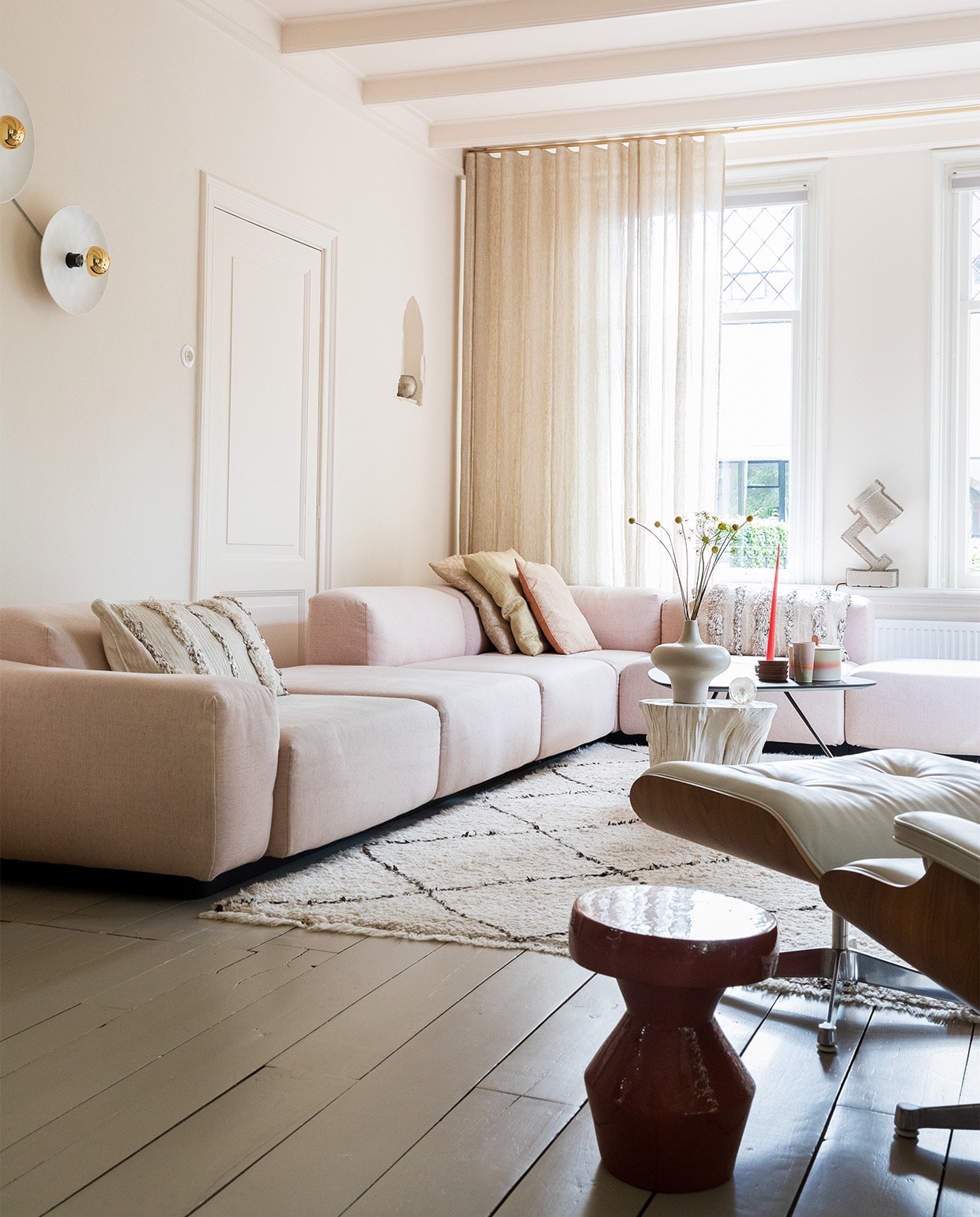 Bank Soft modular van Jasper Morrison en stoel Eames via Vitra. Vloerkleed en kussens links en rechts Household Hardware. Kussens midden Blooming Interior. Witte bijzettafel en vaas van Pols Potten via Wim van Assem bloembinderij. Zwarte bijzettafel Leolux en bijzettafel voorgrond via Eijerkamp.Wanden, deur, plafond kleur Julie’s Dream van Little Greene. Vloer kleur Brown Wood van Vestingh Paint. Papier-maché lamp Tradition via Loods 5. Gordijnen Van den Bosch Interieurstoffen. Messing railroede Corpus van Interstil. Presse papier Hafod Grange. Wandlampen vtwonen. Theebeker en koektrommel HKliving. Onderzetters Ikea. Kaars Ester &amp; Erik.