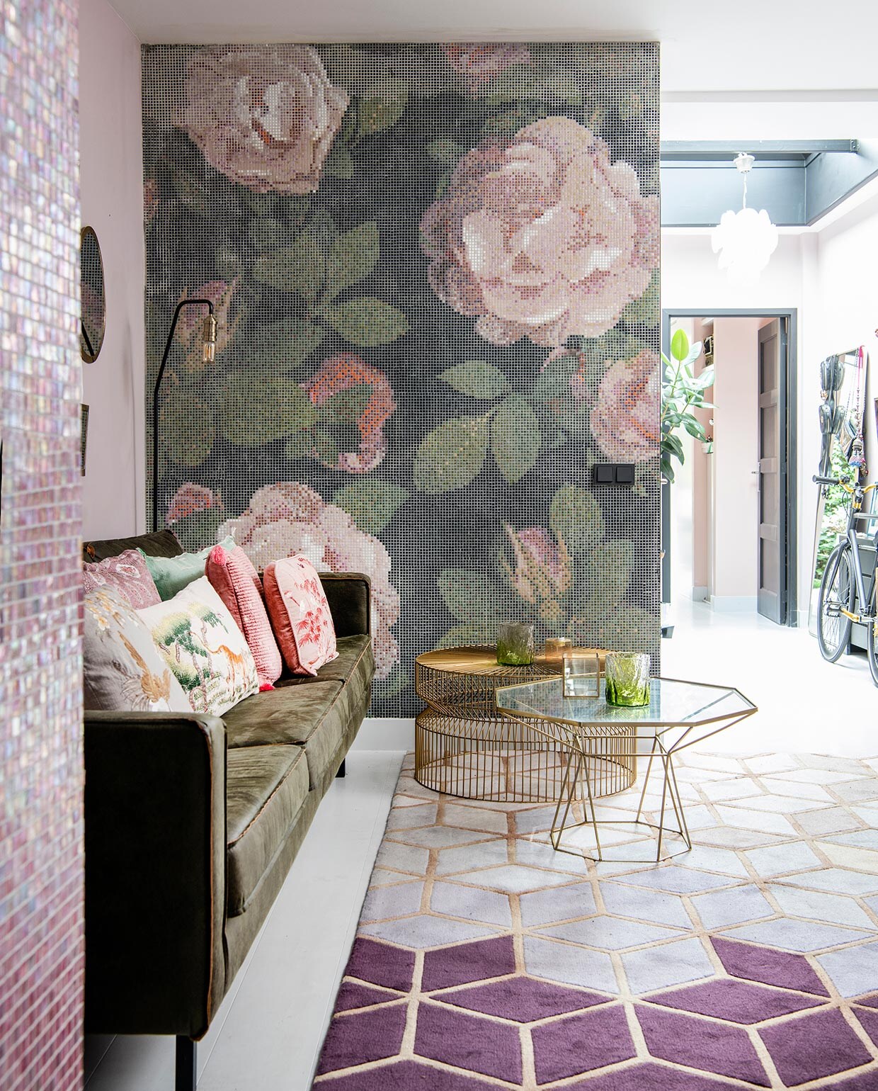 Tegelmozaïek van Bisazza, via Ton Scholten Tegelhandel. Kleed via The Frozen Fountain, tafel met glazen blad van L’Etoile en messing tafel van Zara Home. Glaswerk Household Hardware en Anthropologie. Donkergroene bank van BePureHome, kussens van De Weldaad, vloerlamp van Made.