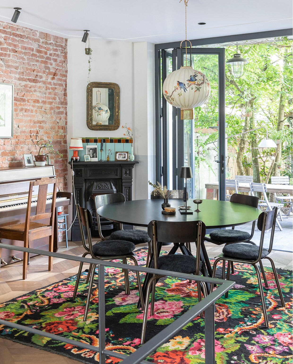De piano was ooit van Philips oma en werd opgeknapt door Philip en Marieke. Foto erboven van fotografe Ata Kandó, gekocht bij Kahmann Gallery. Tas We Are Vintage. Spiegel boven schouw Marktplaats. Oranje lamp, vaasje en fotolijst rommelmarkt. Schouw Jan van IJken Oude Bouwmaterialen. De vintage tegels erboven komen uit een oud zwembad en werden gekocht bij Mammoet. Tafel Studio Henk. Stoelen uit een winkeltje dat niet meer bestaat. Draadloze lamp op tafel Faro Barcelona. Vaasje Loods 5. IJscoupe van een Franse rommelmarkt. Vloerkleed Rozenkelim. Spotjes Brink Licht. Lamp boven de tafel Taiwan-lantern.