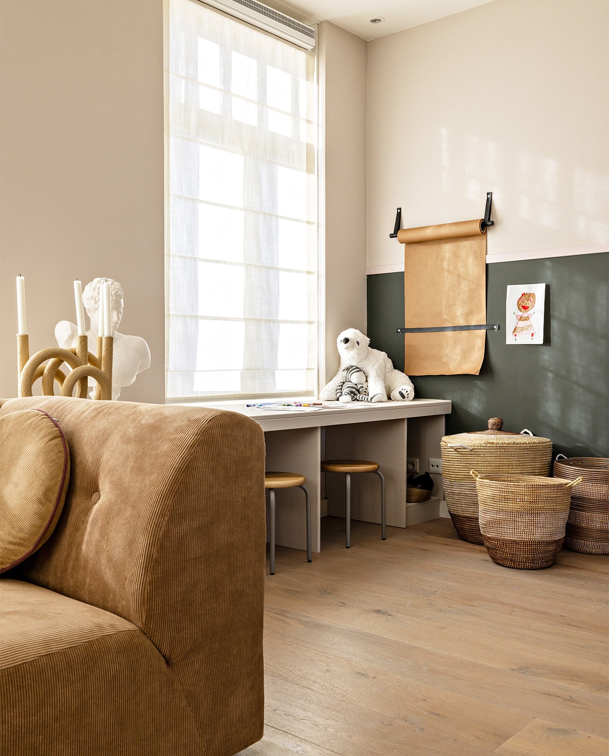 Flexa Creations muurverf Sandy Steps, aan de onderkant Factory Green, dunne streep in het midden Poetic Pink (flexa.nl). Bank van HKliving, per element vanaf € 795,- (eijerkamp.nl). Rond rib kussen van HKliving € 34,95, kandelaar van pt,€ 82,50, papieren rol van vtwonen € 29,95, krukken van Kidsdepot, set van 2 € 79,90 (vtwonen.nl). Wit beeld € 85,- (het-schippertje.nl). Opbergmanden, prijs op aanvraag (basketsbeadsbasics.nl). Overig privébezit.