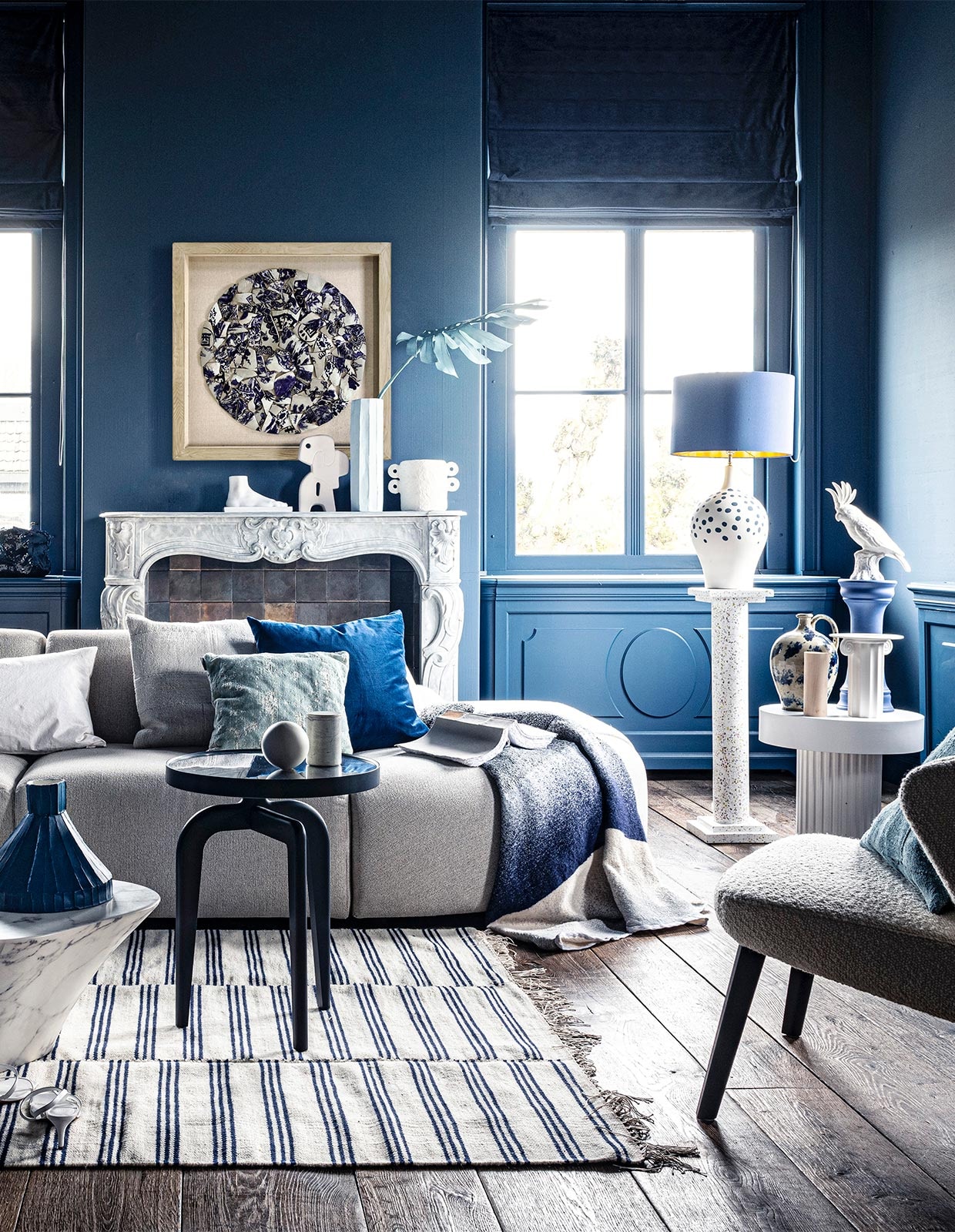 Voet op schouw € 59,95, sierobject op schouw € 58,95, pilaar € 239,-, witte bijzettafel € 269,-, witte vaas € 38,35, schilderij prijs op aanvraag (hkliving.nl). Velours stoel € 1200,- (edha-interieur.nl). Kleed € 199,- (zarahome.com). Marmeren salontafel € 587,50, blauwe tak € 57,- (polspotten.nl). Blauwe salontafel van Schönbuch € 719,-, plaid van Mae Engelgeer € 440,-, wit kussen van Mrs.me € 99,- (homestede.nl). Blauw kussen € 49,-, ecru kussen € 49,-, blauw kussen op stoel € 49,- (couleurlocale.eu). Wandlamp Chicago van It’s about RoMi € 355,-, kussen Sarona vintage blue, 45×45 cm € 35,- (polspotten.nl). Velvet sierkussen, 55×55 cm € 74,-, donkerblauwe vaas met tak (klevering.nl). Zeshoekige vaas, hoogte 32 cm € 38,99, Kaketoe ornament € 53,-(polspotten.nl), bank Jax van HKliving, element vanaf € 499,- (vtwonen.nl). Blauwe vaas, smal toelopend € 469,-, cirkelvormig sierobject € 129,-, wit bakje op tafel, prijs op aanvraag, lichtblauwe vaas, hoogte 46 cm € 239,-, marmeren pot op blauwe salontafel € 45,-, opengeslagen boek € 40,- (badenbaden.nl). Stoel rechts € 1898,-, sierbal op blauwe tafel, set van 3 € 99,-, houten siervorm op bijzettafel, set van 3 € 99,- (covanderhorst.nl). Schoenen € 34,99 (hm.com). Lampenvoet met stippen € 798,-, gordijnstof 295 cm breed, per meter € 103,- (wva.nl). Blauw gevlekte vaas op bijzettafel € 235,95, blauwe kleine pilaar € 66,55, blauwe lampenkap € 332,75, wandbord per 2 € 235,95, marmeren schouw Lodewijk XIV € 15.125,-, 18e-eeuwse houten vloer, per m² € 168,19 (pietjonker.nl). Witte vaas van Serax op schouw € 40,85 (loods5.nl). Overig privébezit.