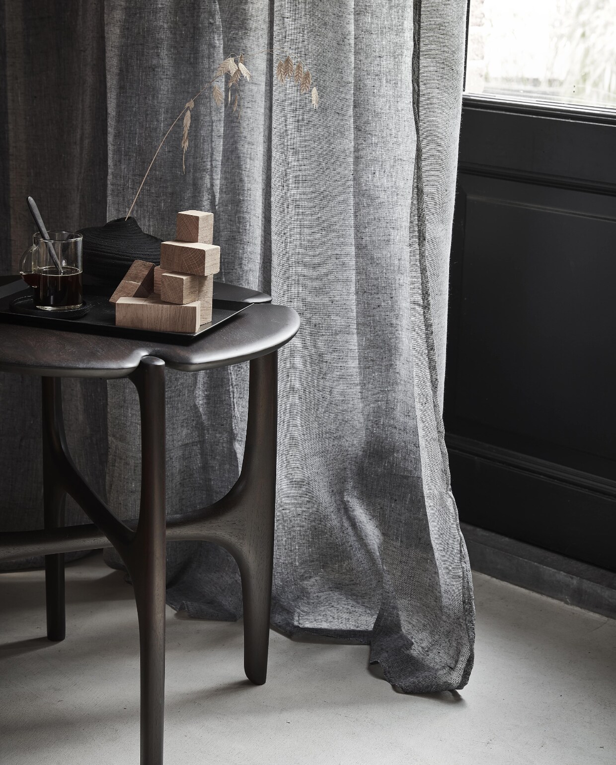 Grijs gordijn Frost, half transparant, met plooi, 270×140 cm (hxb) € 44,99M.m.v. vanbinnen.com (bijzettafel), zarahome.com (houten blokspel, metalen dienblad, espressokopje), hm.com/home (zwart vaasje). Overig privébezit.