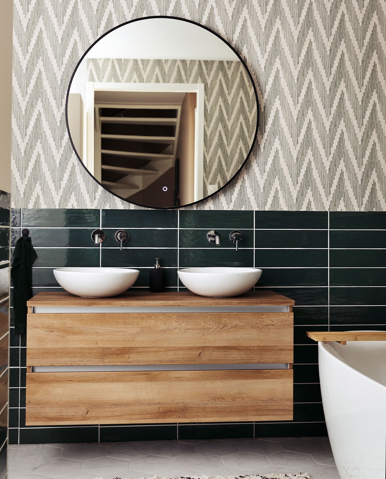 Badkamerkast Unihopper. Wastafelkommen Solid Surface. Kranen en vrijstaand bad ADW. Spiegel Best Design. Tegels Sartoria. Behang BN Walls. Kleed H&amp;M Home.
