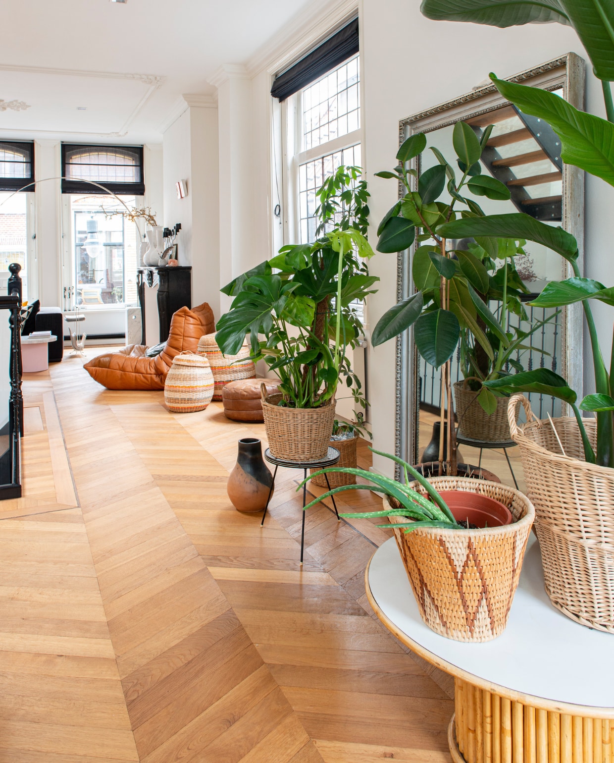Rotan tafel, manden, plantenpotten, plantentafel en poef via kringloopwinkel en rommelmarkten, vaas op vloer gemaakt door oma.