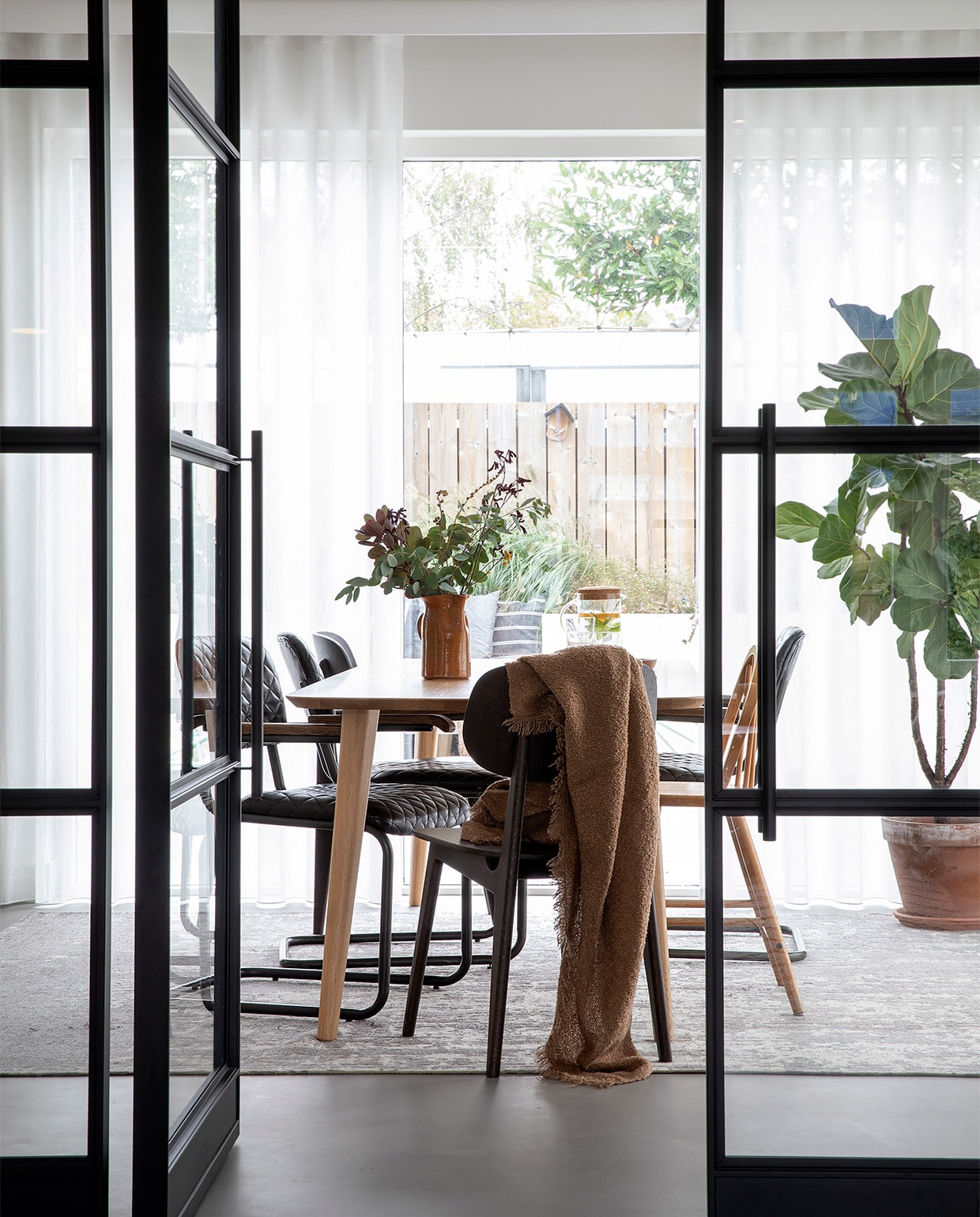Deuren met stalen kozijn op maat gemaakt door Wout Jansen. Tafel Sav &amp; Økse. Stoelen By-Hoo. Hoge kinderstoel Ikea via Marktplaats. Vloerkleed Floorpassion. Plaid H&amp;M Home. Vaas van de kringloopwinkel.