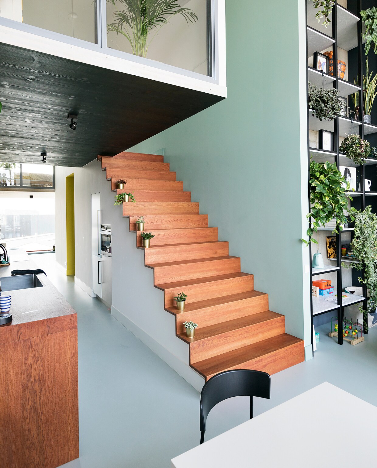 Maatwerkkeuken, eikenhouten trap en stalen kast ontwerp Martijn Frank Dirks, uitvoering Spinder Interieurbouw. Vloer DGF polyurethaan PU Gietvloer in kleur NO.05.65 via Design Gietvloer Amsterdam. Gouden bloempotten Ikea. Grijze verf Sikkens ACC Aqua Zijdeglans kleur SN.02.57.
