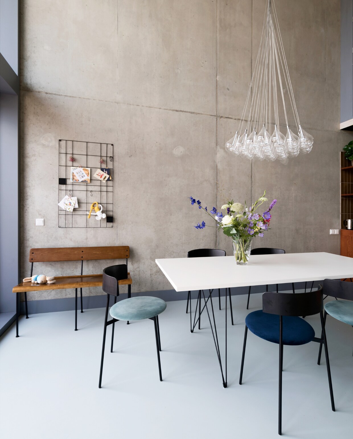 Schoolbank Teach en memobord Wire van vtwonen. Hanglamp Lightsonline. Eetkamerstoelen Friday van Fest. Tafel Magis Tavolo XZ3 via Flinders. Vloer DGF polyurethaan PU Gietvloer in kleur NO.05.65 via Design Gietvloer Amsterdam. Betonnen muren geïmpregneerd met Hydrablock Pro voor matte look.
