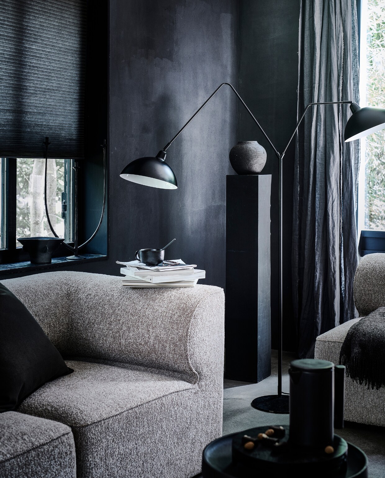 Matzwarte metalen vloerlamp Orion, 180×140 cm (hxb), kap en voetplaat 31 cm (Ø) € 239,95.M.m.v. designtales.nl (modulebank, fauteuil, theepot en mok van Menu), loods5.nl/design (metalen bijzettafel), hm.com (zwarte vaas, bruine plaid), sissy-boy.com (kandelaar), zarahome.com (keramieken bolvaas), bymolle.com (linnen gordijnen in kleur Slate). Overig privébezit.