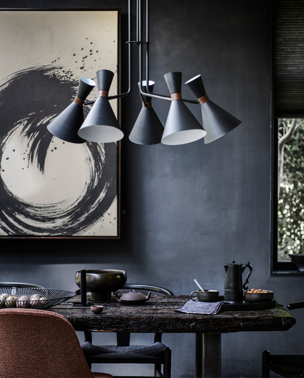 Matzwarte metalen hanglamp Hoodies, 86,5×89 cm (Øxh) (ook verkrijgbaar in mat zandgrijs).M.m.v. tessaderijk.com (schilderij), loods5.nl (zwarte eetkamerstoelen), designtales.nl (bruin gestoffeerde eetkamerstoel, schaal en kom van Menu), vtwonen.nl (opengewerkte schaal van Serax), simonlevelt.nl (bruine keramieken theepot met kopje), letoile.store (theedoek), paviljoennoord.com (mok, koffiepot). Overig privébezit.