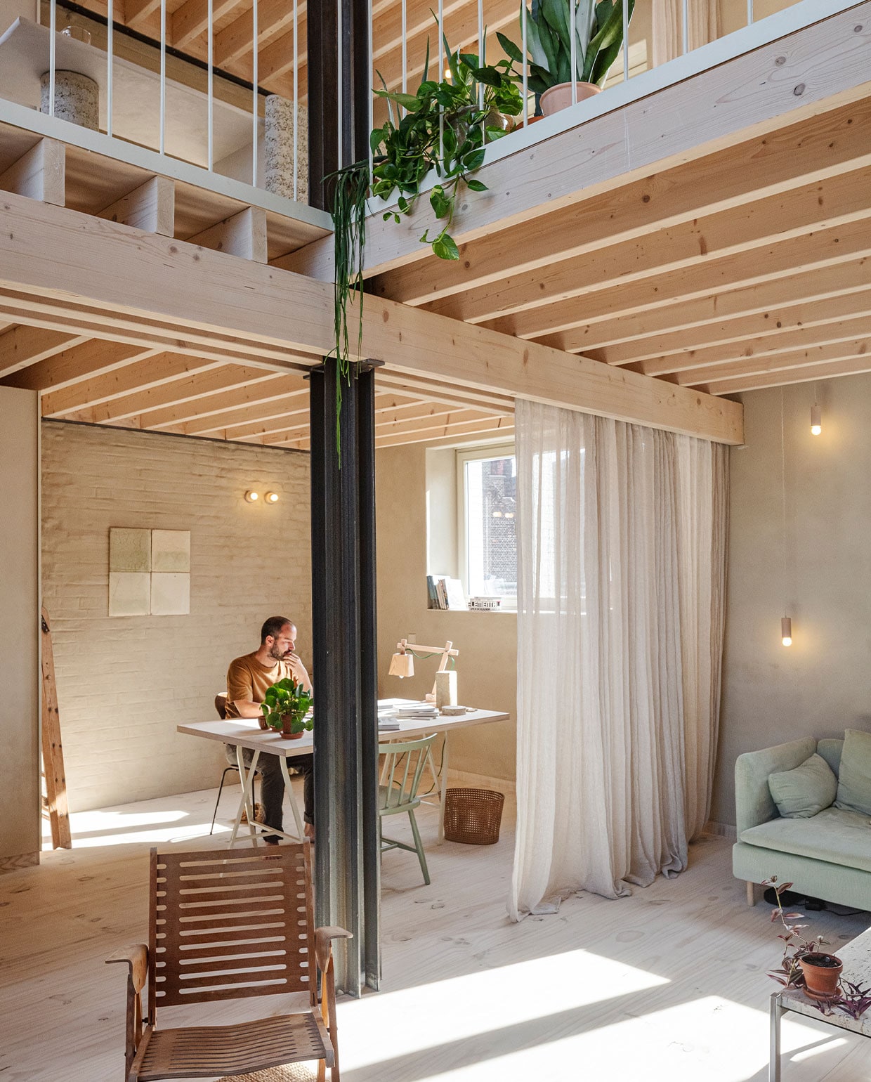 Bureau met multiplex blad op schragen van Ikea. Stoelen, prullenbak en ladder gekregen van Hanne’s oma. Verlichting gemaakt door de vader van Nicolas. Bureaulamp Muuto. Aan muur proefstalen van leempleister met algen voor een project van BC Materials. Stoelen Niko Kralj.