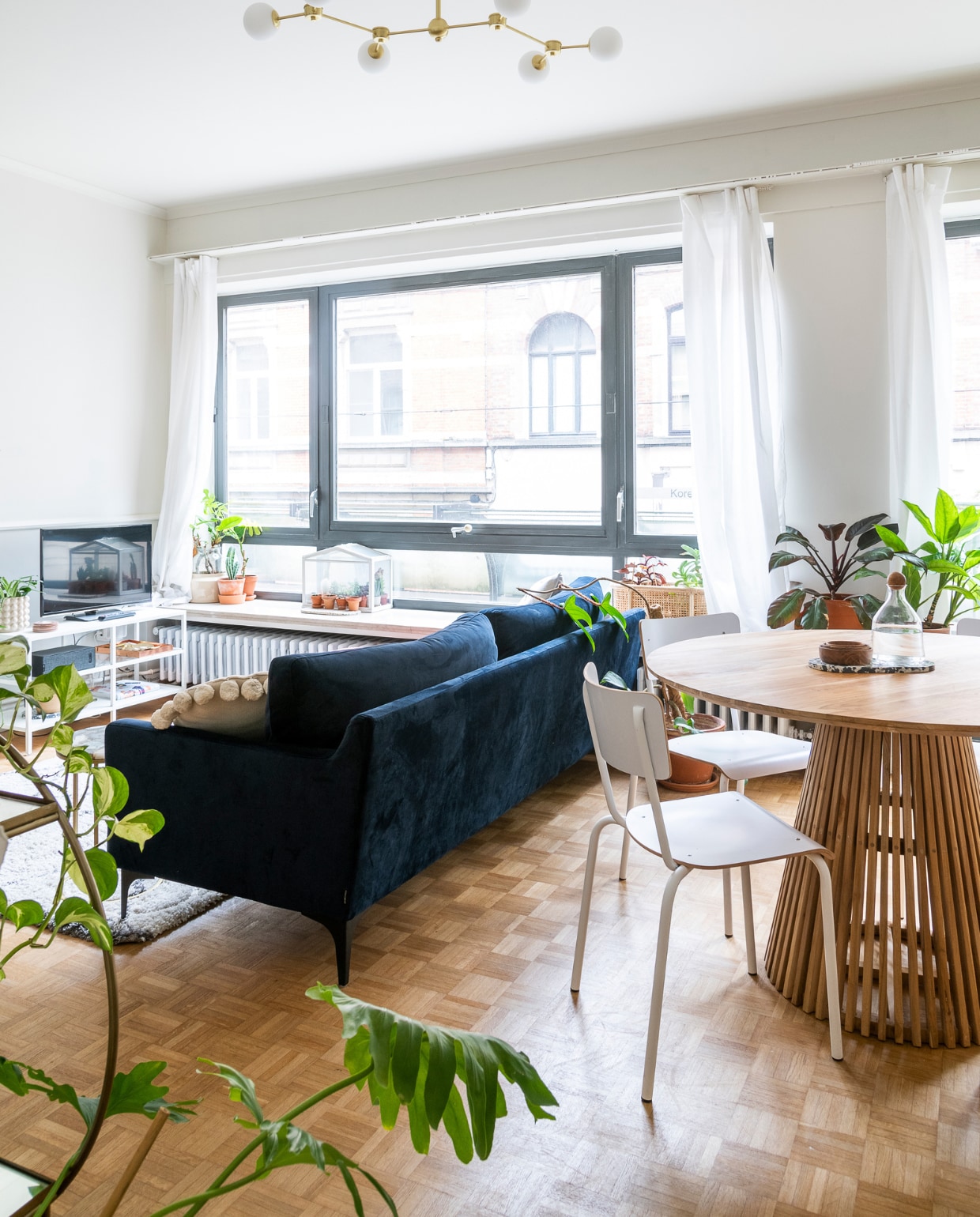 Blauwe bank Sofa Company, laag wit rek Ikea, speaker Sonos, serrekastje Ikea, rotan bloempot H&amp;M Home. Stoelen Perfecta, ronde tafel Fonq. Planten Broese. Overig onbekend.