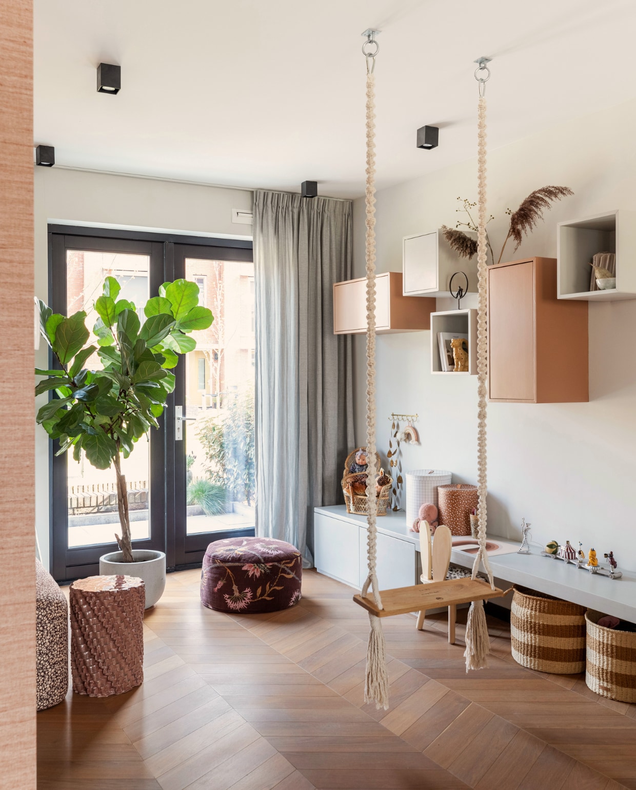 Schommel CreaMePassion, bank links HKliving, keramische kruk Floris Wubben, gordijnen Kwantum, zwarte plafondspots Qazqa, lage wandbank eigen ontwerp, hangkasten Ikea, geverfd in kleuren French Grey Mid van Little Greene en D8.24.44 van Sikkens, gebloemde poef Sissy-Boy, stoeltje Petite Amélie, manden en opruimdozen Oyoy. Overig onbekend.