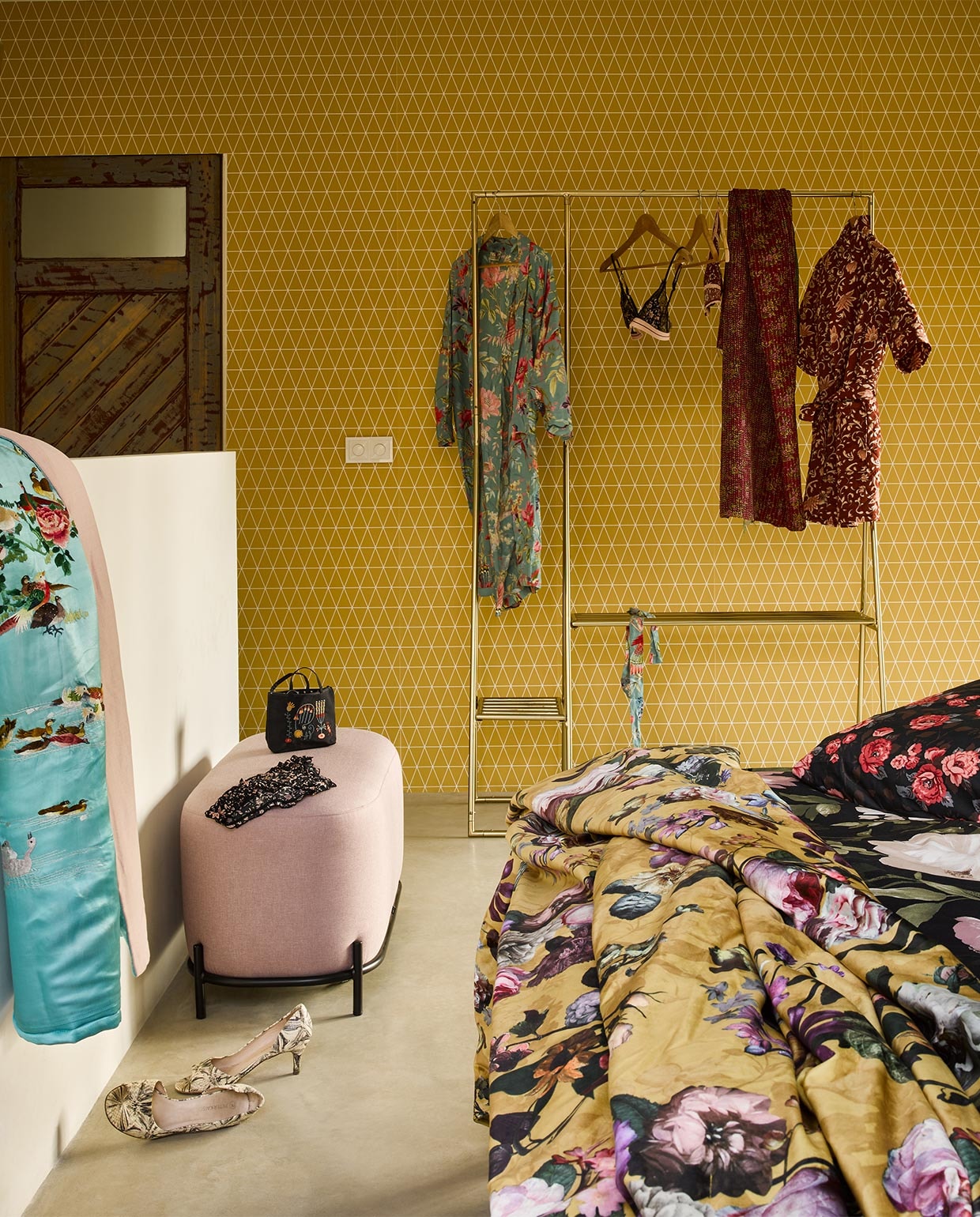 Behang Superfresco Easy, per rol vanaf € 24,95 liter (gamma.nl). Dekbed-overtrek Blekfryle, 200×200 cm € 49,95, dekbedovertrek Backvicker, 200×200 cm € 39,95 (ikea.nl). Gele sprei Fleur van Essenza, 170×135 cm (lxb) € 84,99, kledingrek van HKliving € 349,-, oudroze poef van HKliving, 45x80x40 cm (hxbxd) € 275,- (vtwonen.nl). Zijden plaid € 450,-, zijden sjaal (aan rek) € 79,-(brechtjeolsthoorn.nl). Blauwe gebloemde kimono € 175,-, rode gebloemde jas € 79,95, beha € 60,-, slip (op poef) € 30,-, tasje (op poef) € 19,95 (maisonnl.com). Schoenen privébezit.