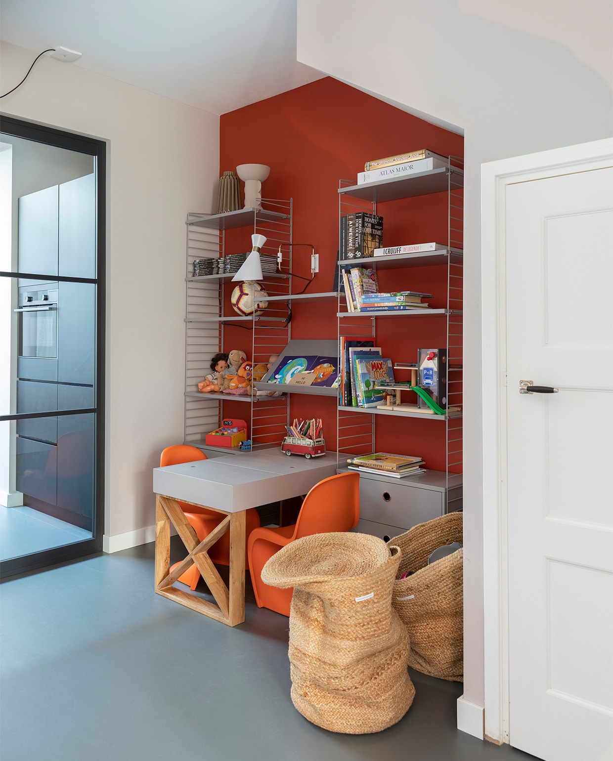 Flexa Creations muurverf C.5.39.34, lak op de kindertafel Mooi Makkelijk Mooi Warmgrijs (flexa.nl). Vloer Marmoleum Walton in de kleur Paving prijs op aanvraag (woninginrichting-aanhuis.nl). Kindertafel zelfgemaakt. Kast van String € 2281,-, stoelen van Vitra, per stuk € 180,- (eijerkamp.nl). Manden per stuk € 59,95 (urbannatureculture.com). Beige vaas linksboven € 35,- (zenza.nl). Lamp van Zuiver € 99,-, rond magneetbord van pt € 31,95 (vtwonen.nl). Overig privébezit.