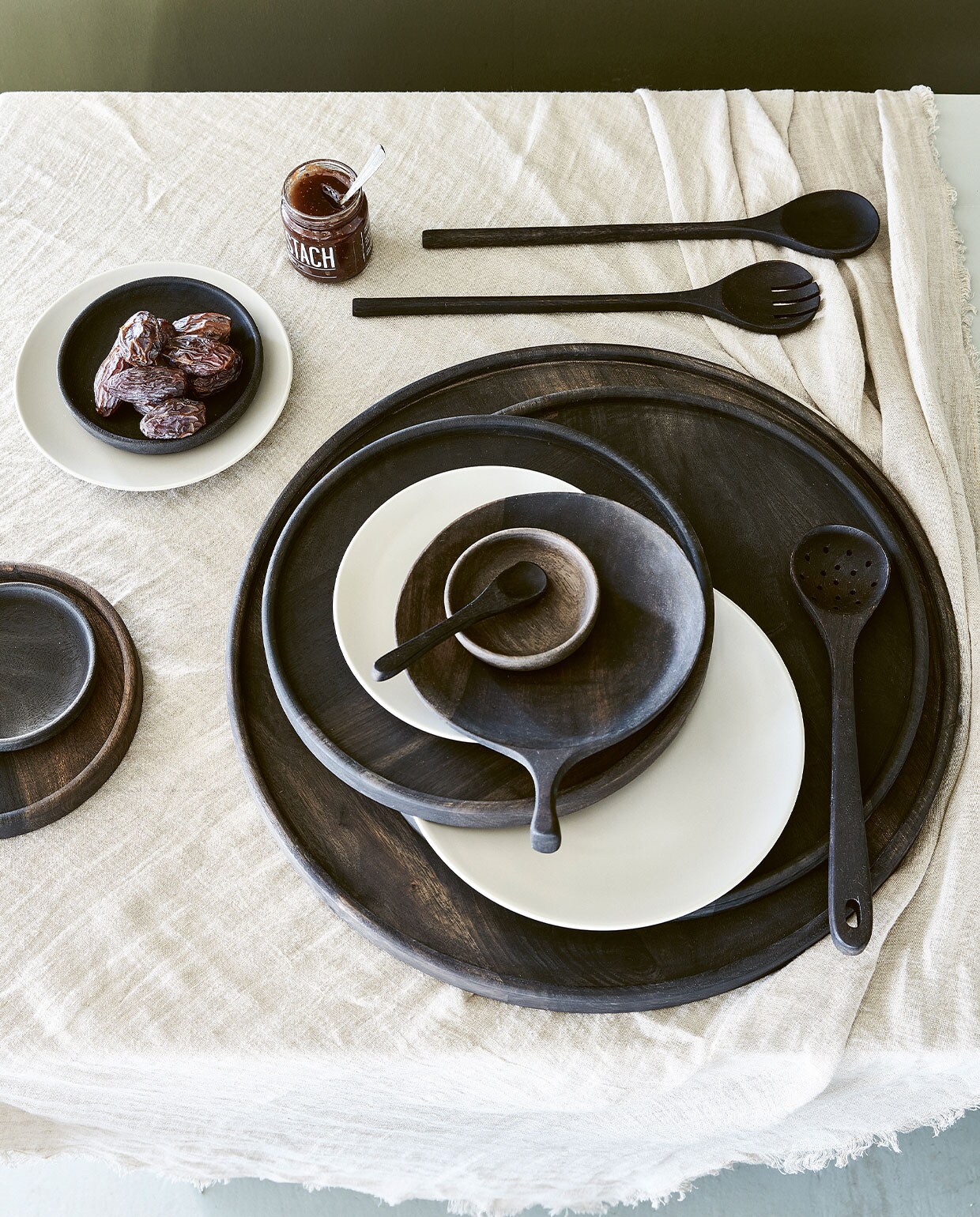 Zwart acaciahouten saladebestek, set van 2 € 14,95. Zwarte acaciahouten lepels, set van 2 € 12,95. Diverse mangohouten borden en kommen vanaf € 12,95. Eiwitkleurig katoen- linnen tafelkleed, 150×250 cm € 59,95. Wit porseleinen bord, vanaf 12 cm (Ø) € 3,50.